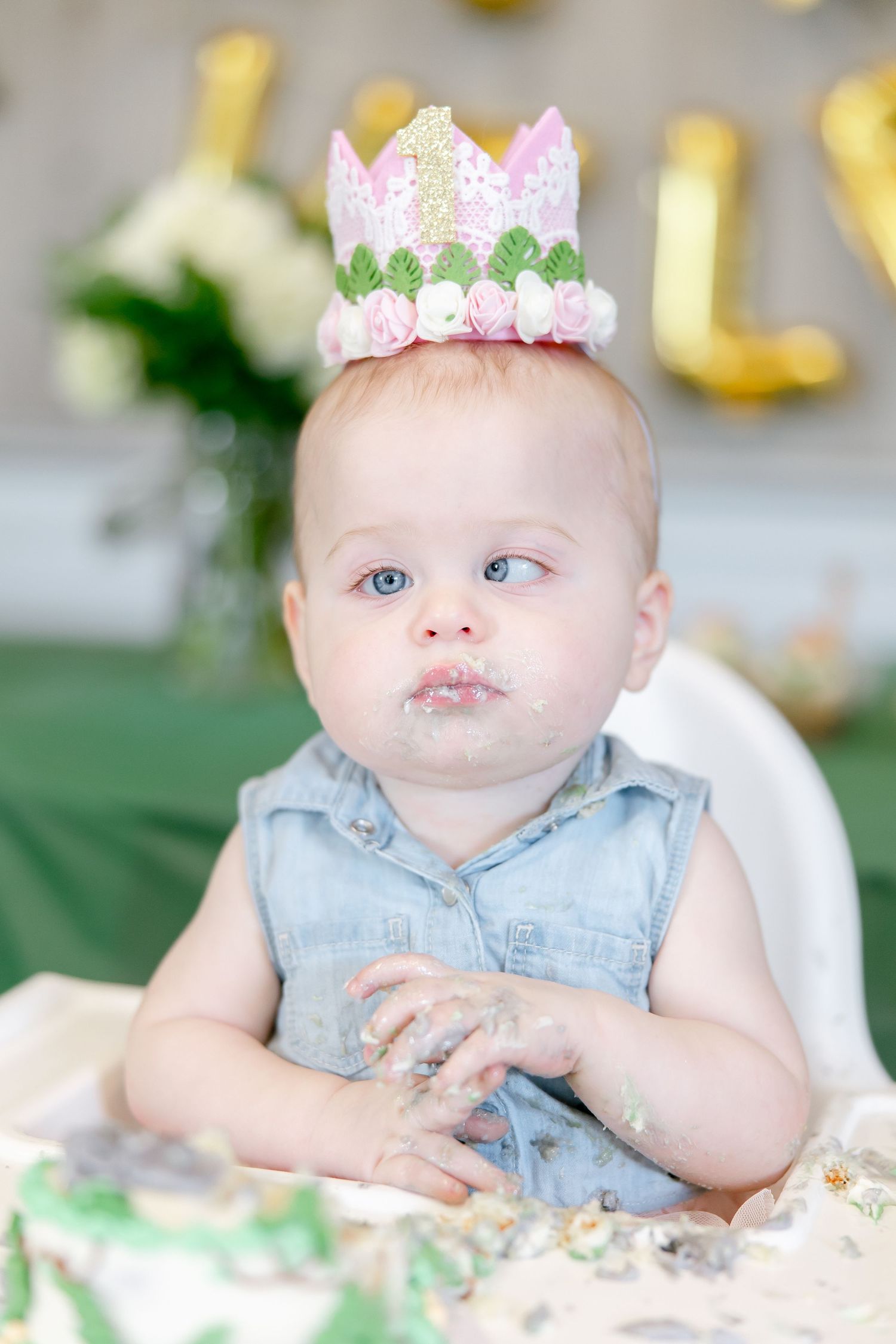 Baby in denim top wearing pink and white lace crown during cake smash.