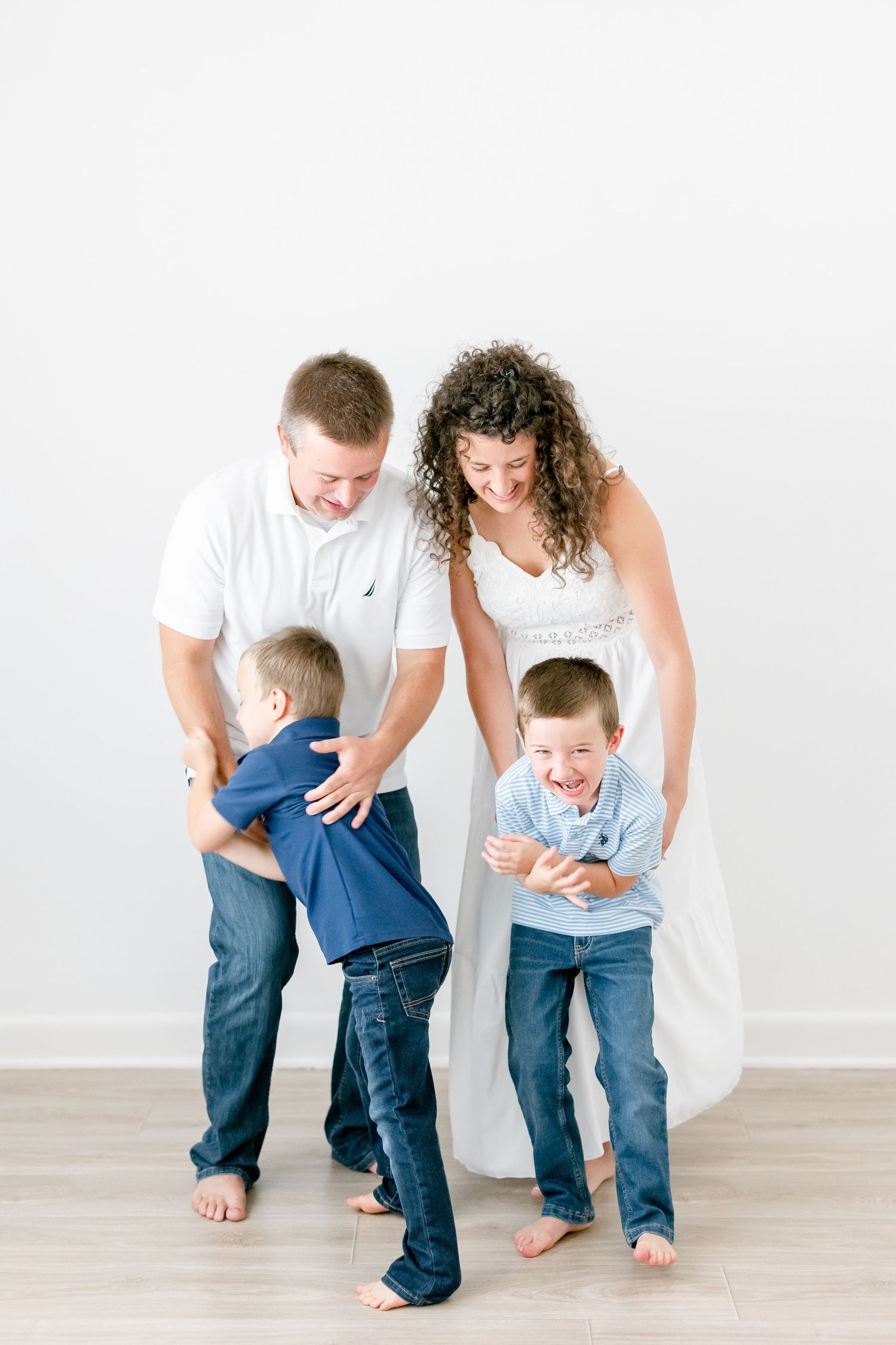 Casual family portraits show playful interactions and candid moments in a bright white studio space.