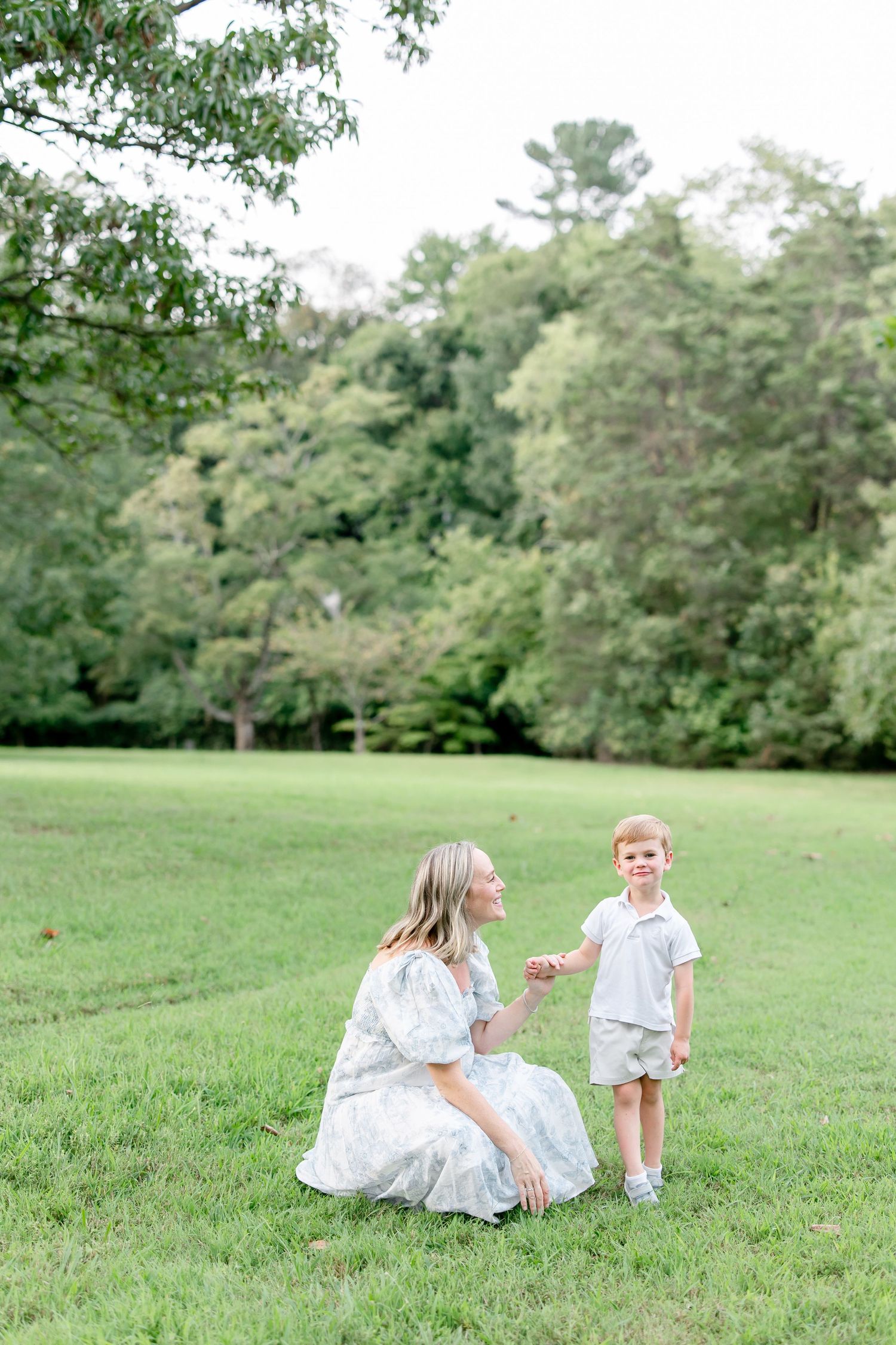 Family enjoying playtime together on a grassy slope with trees in the background.