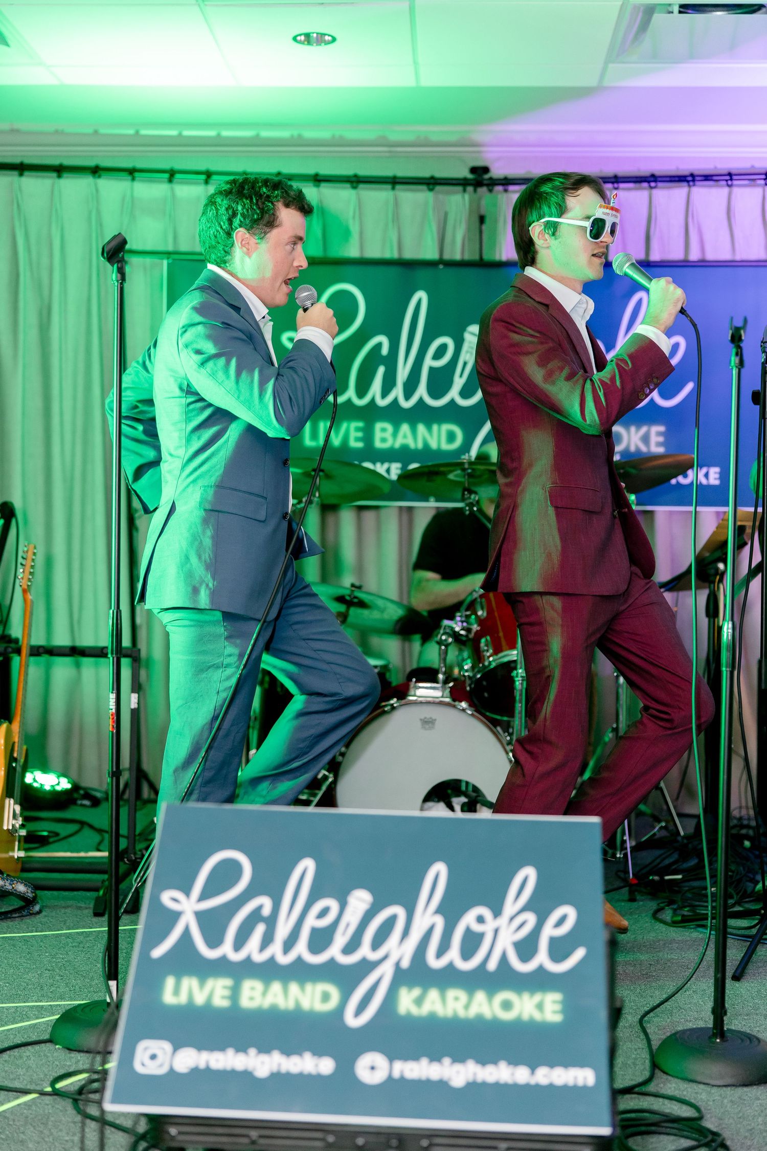 Live band performing on stage with neon signage and colored lighting effects.
