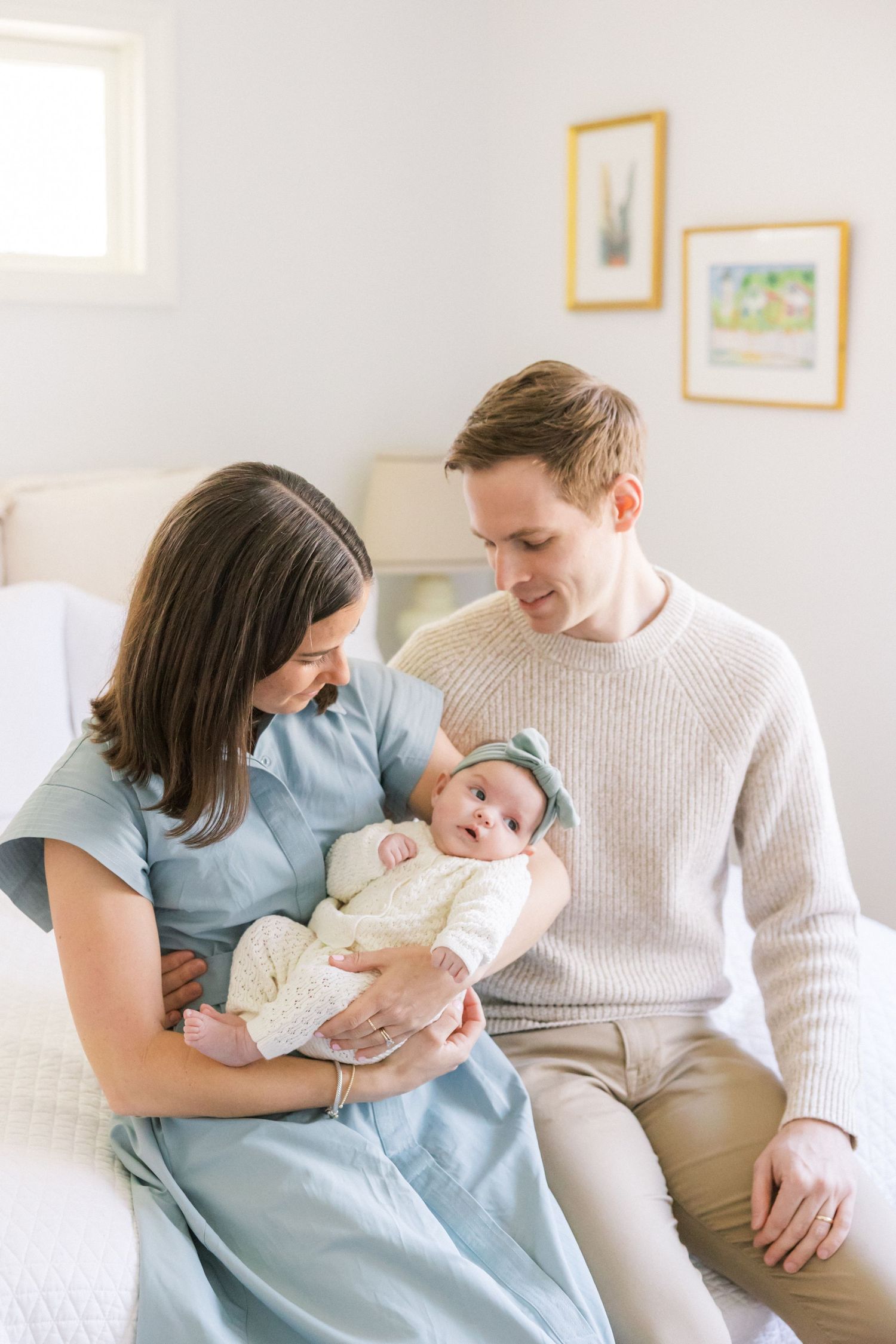 Young family sharing tender moments together on white couch during newborn photoshoot.
