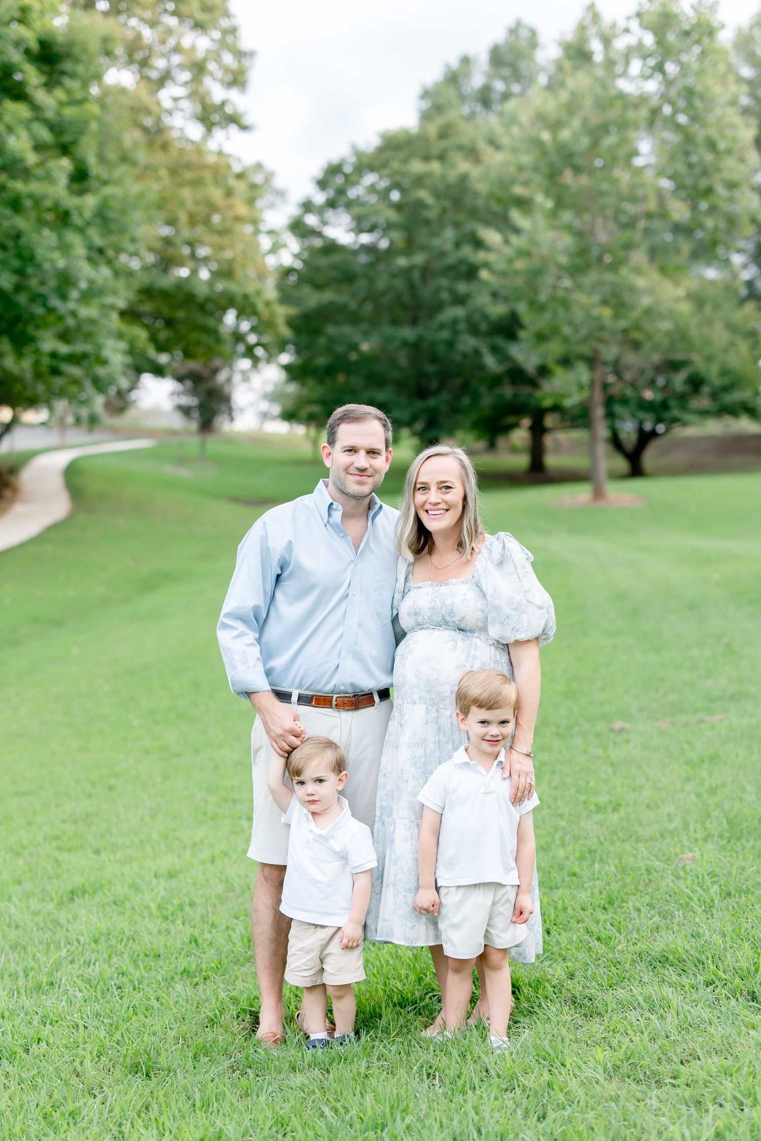 Family group wearing matching blue and white outfits poses together on a green hillside.