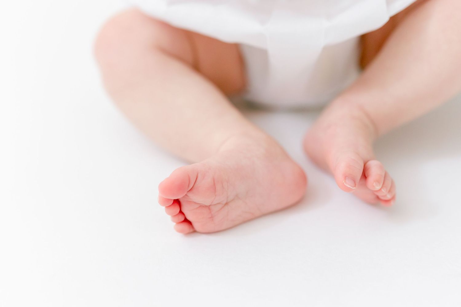 Close-up of cute baby feet and toes on a white background, perfect for newborn photography concepts.