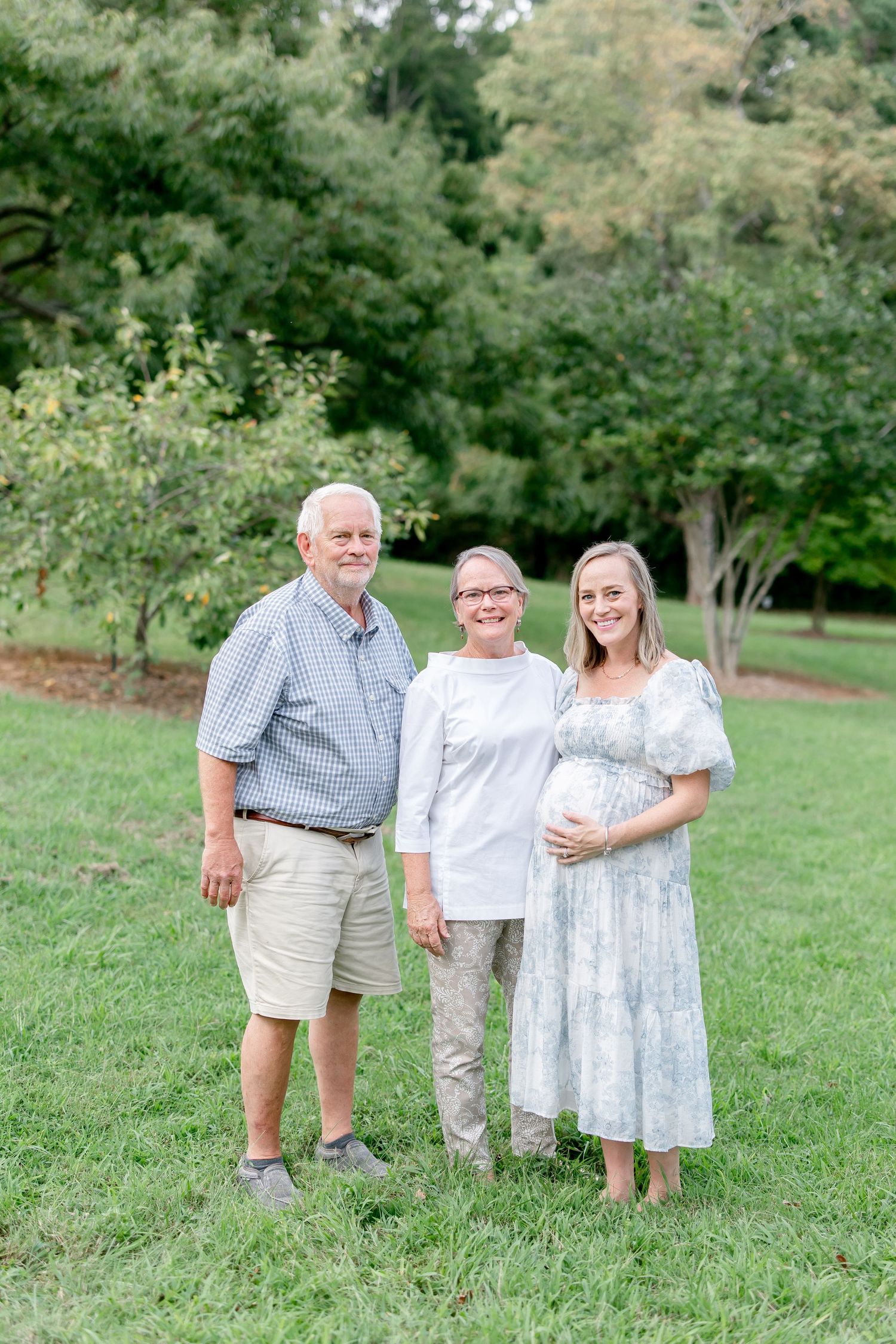 Extended family group in coordinating casual outfits poses together on grassy hillside.