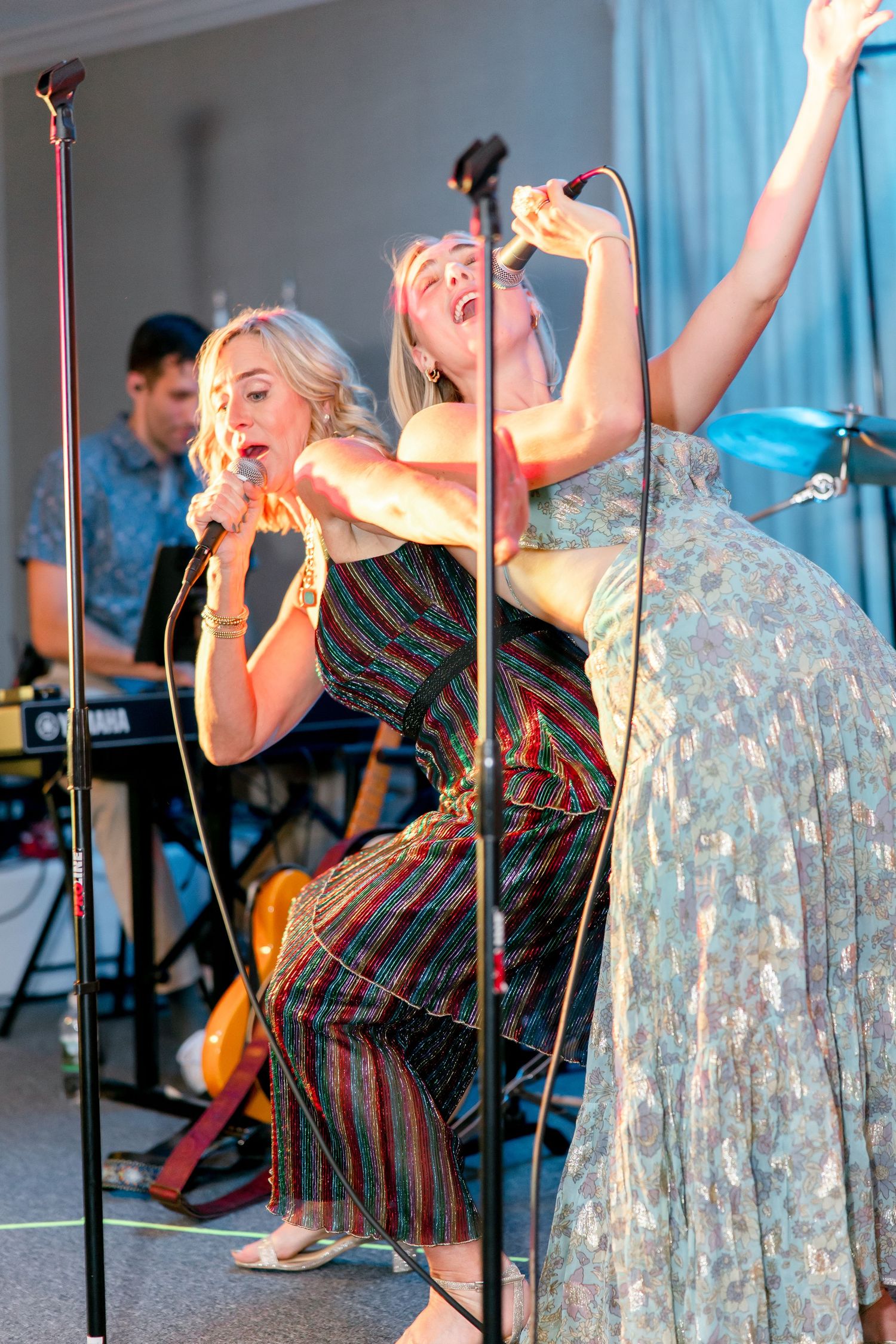 Entertainers performing energetically on stage with microphones during live music show.