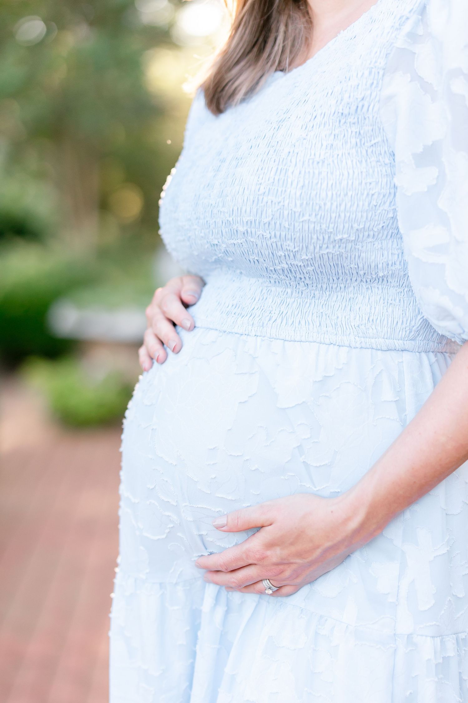 Close-up details of a light blue maternity dress showing the growing baby bump.