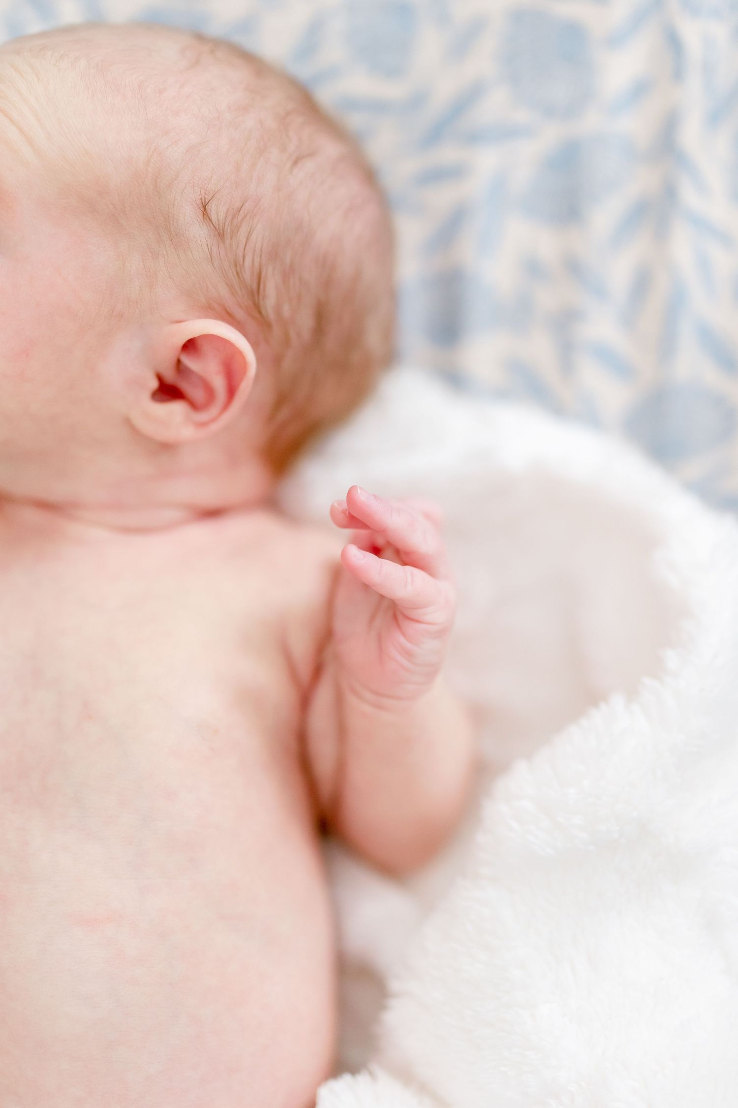 Close-up macro shots of a sleeping newborn baby's delicate features against soft white bedding.