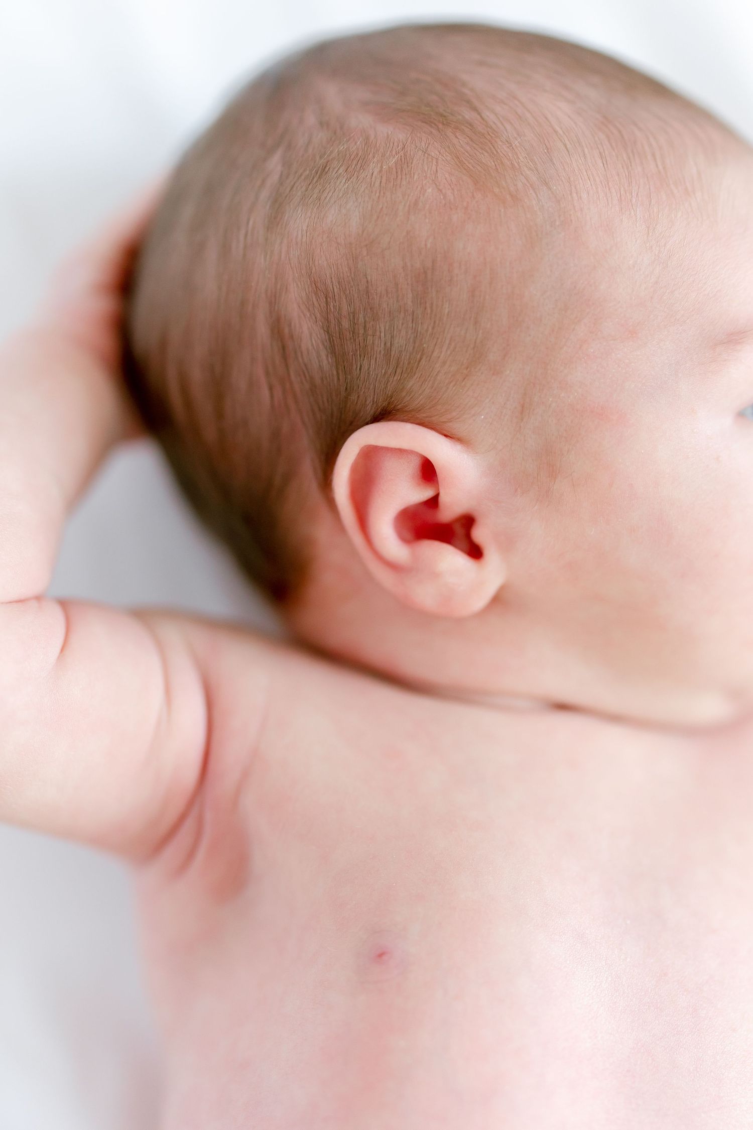 Close-up view of a baby's ear and side of head showing delicate skin and soft hair.