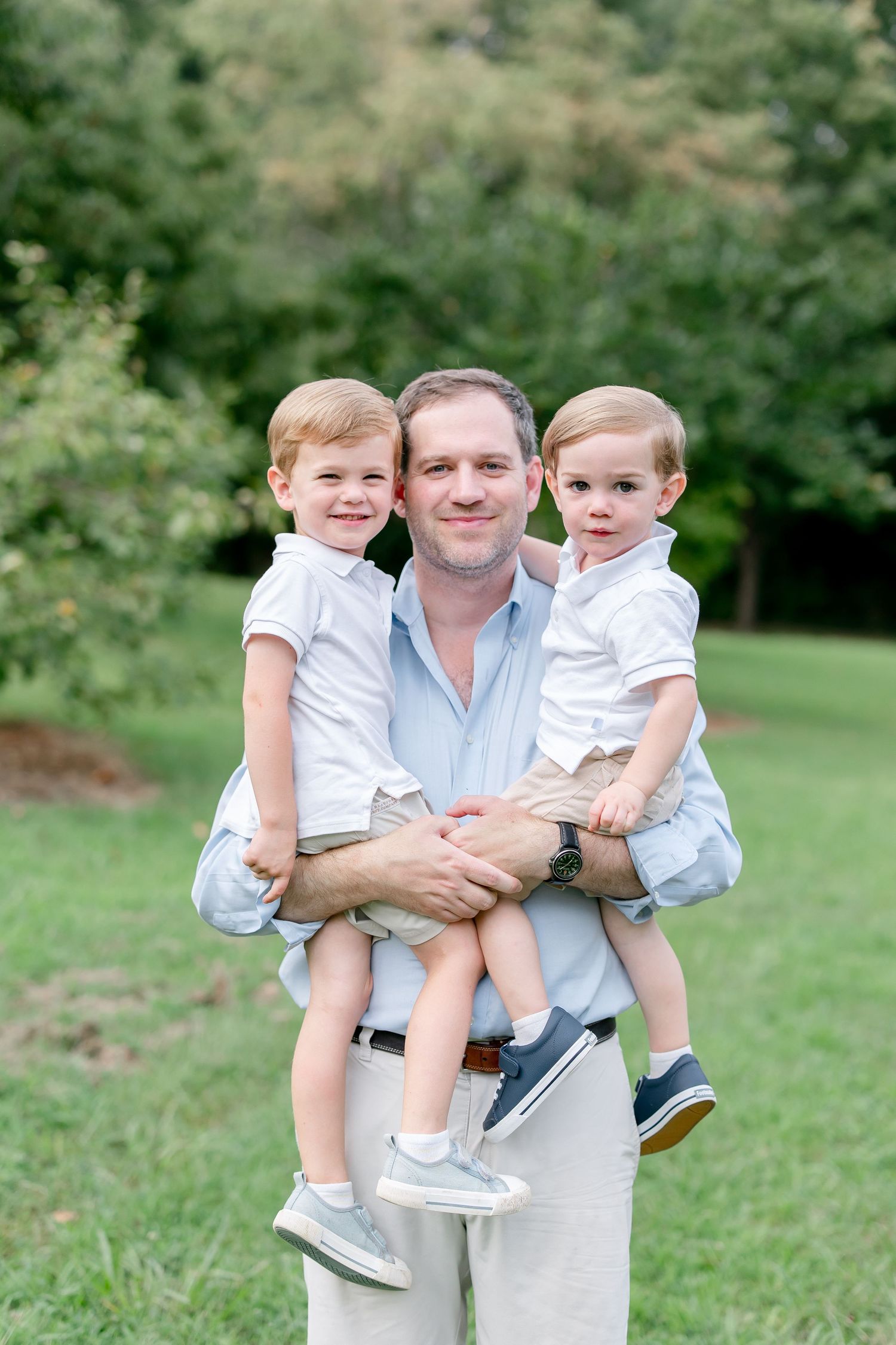 Family portrait with matching outfits standing together on grassy lawn.