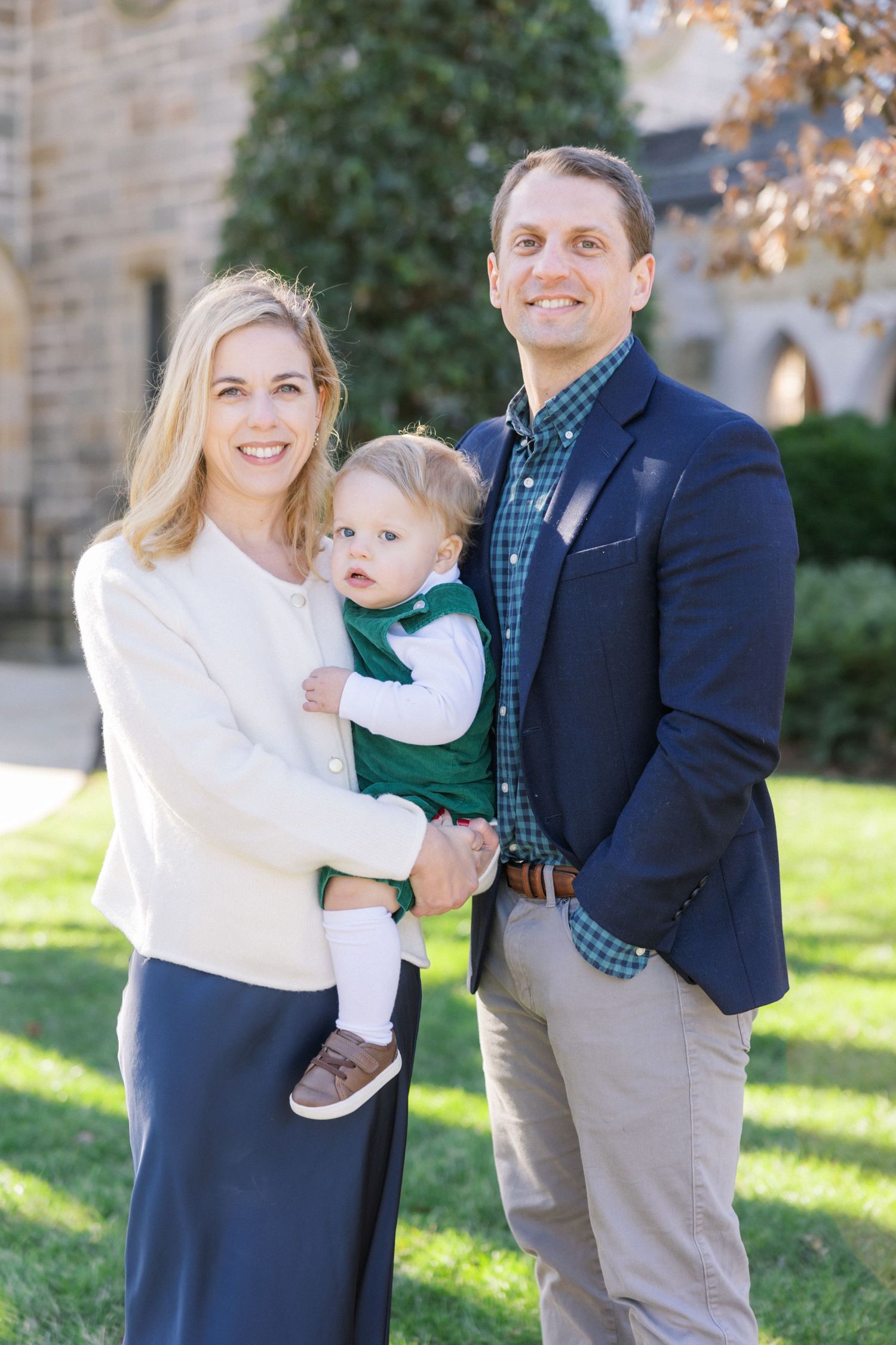 A family poses together on a sunny autumn day wearing coordinated outfits in navy and white.