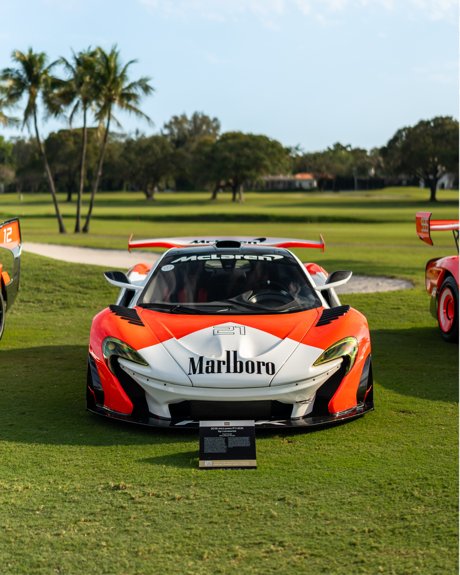 McLaren P1 GTR in Marlboro livery displayed on a golf course during a concours-style car show