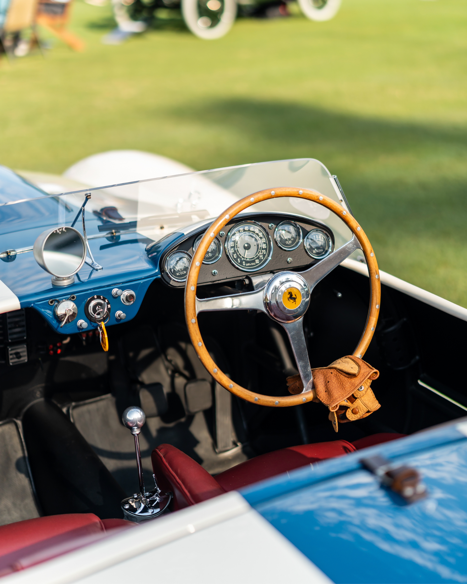 Close-up of a vintage Ferrari convertible dashboard featuring a wooden steering wheel and classic analog gauges