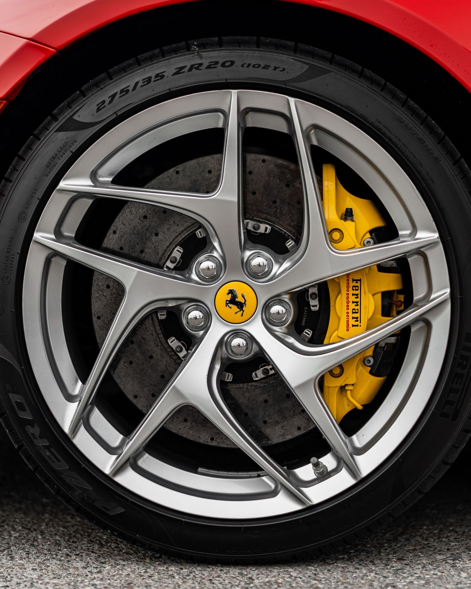 Close-up of a Ferrari 812 front wheel featuring silver alloy spokes and yellow carbon ceramic brakes