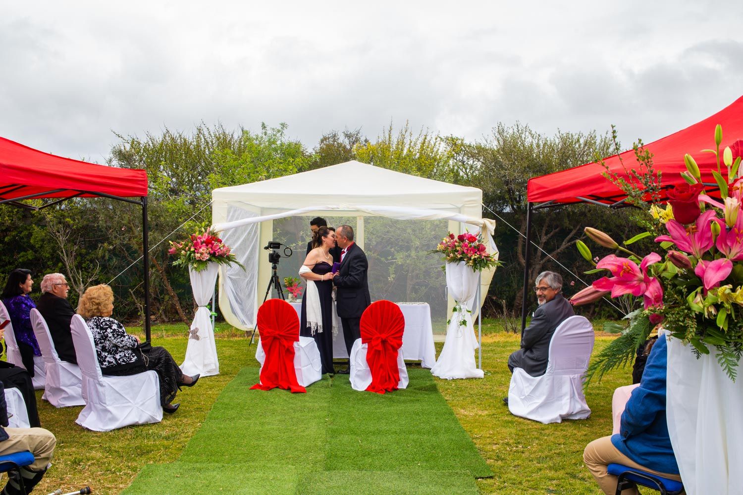 Bride and groom kissing at the altar during an outdoor wedding ceremony on grass.