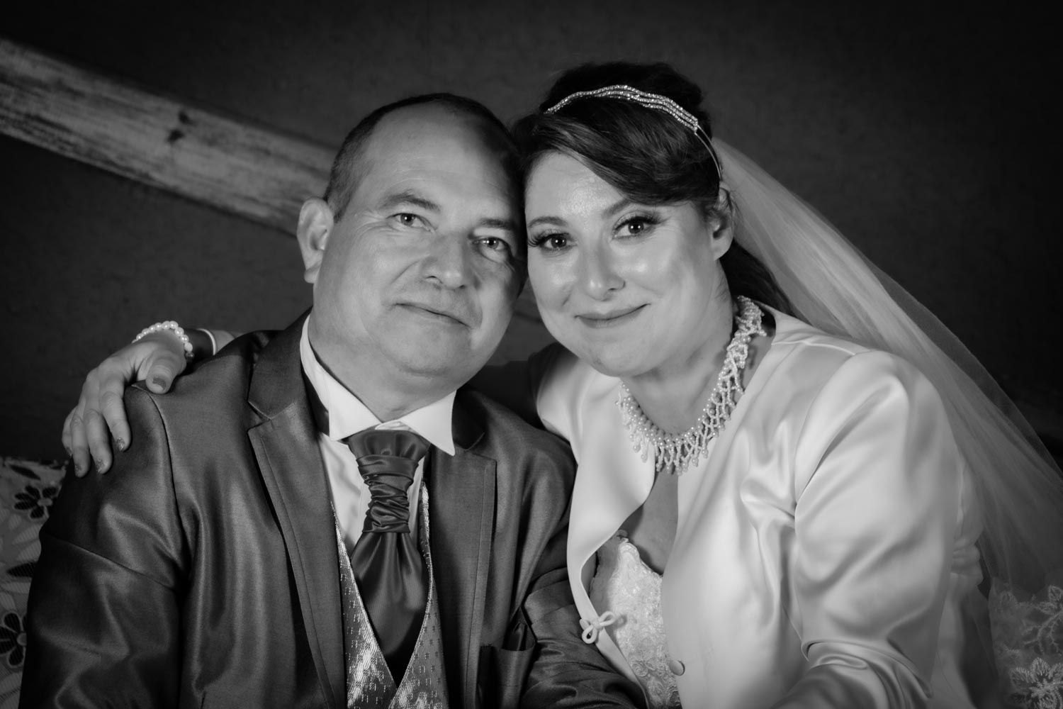 Black and white portrait of smiling bride and groom posing together at wedding reception.