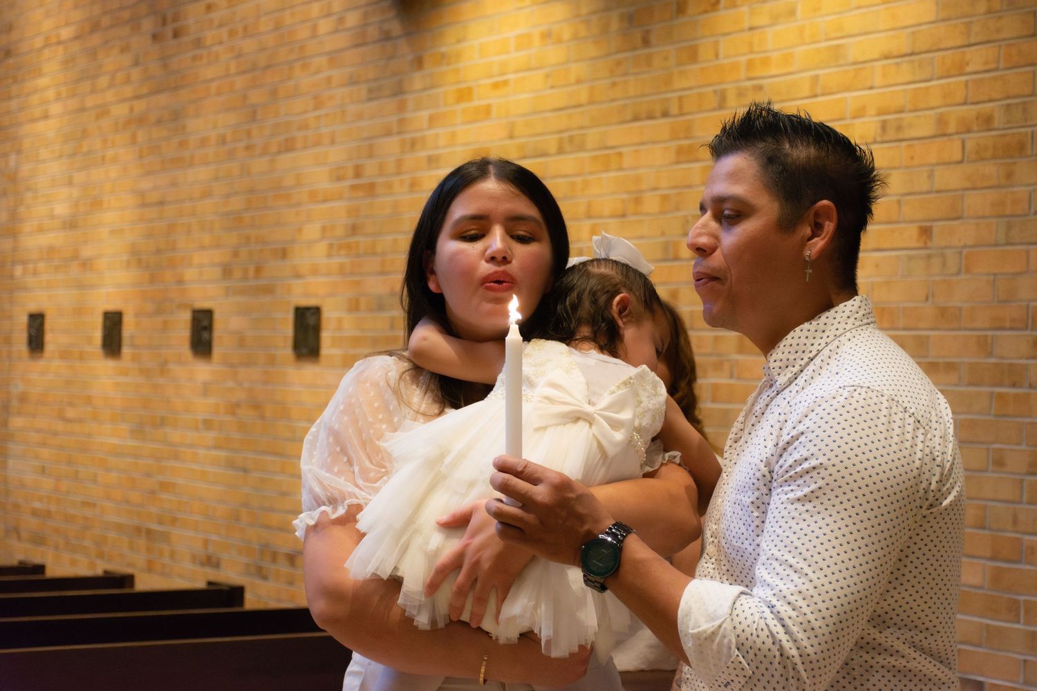 Family blowing out baptism candle during christening ceremony in a church.