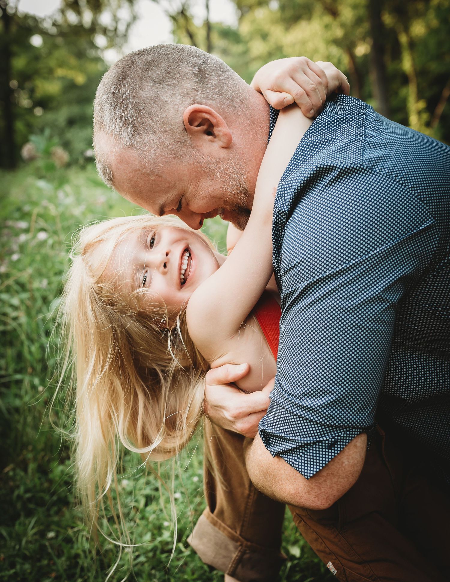 Intimate outdoor family moment captured in natural lighting among greenery.