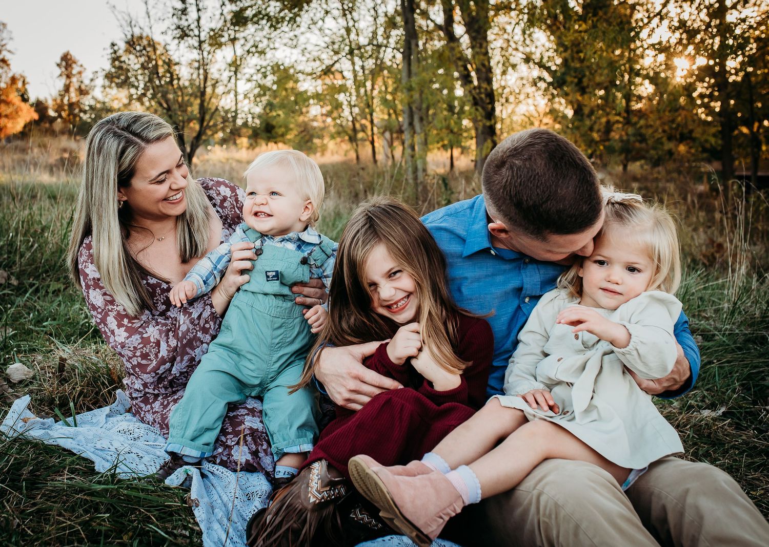 A candid family moment captured during sunset in a grassy field.