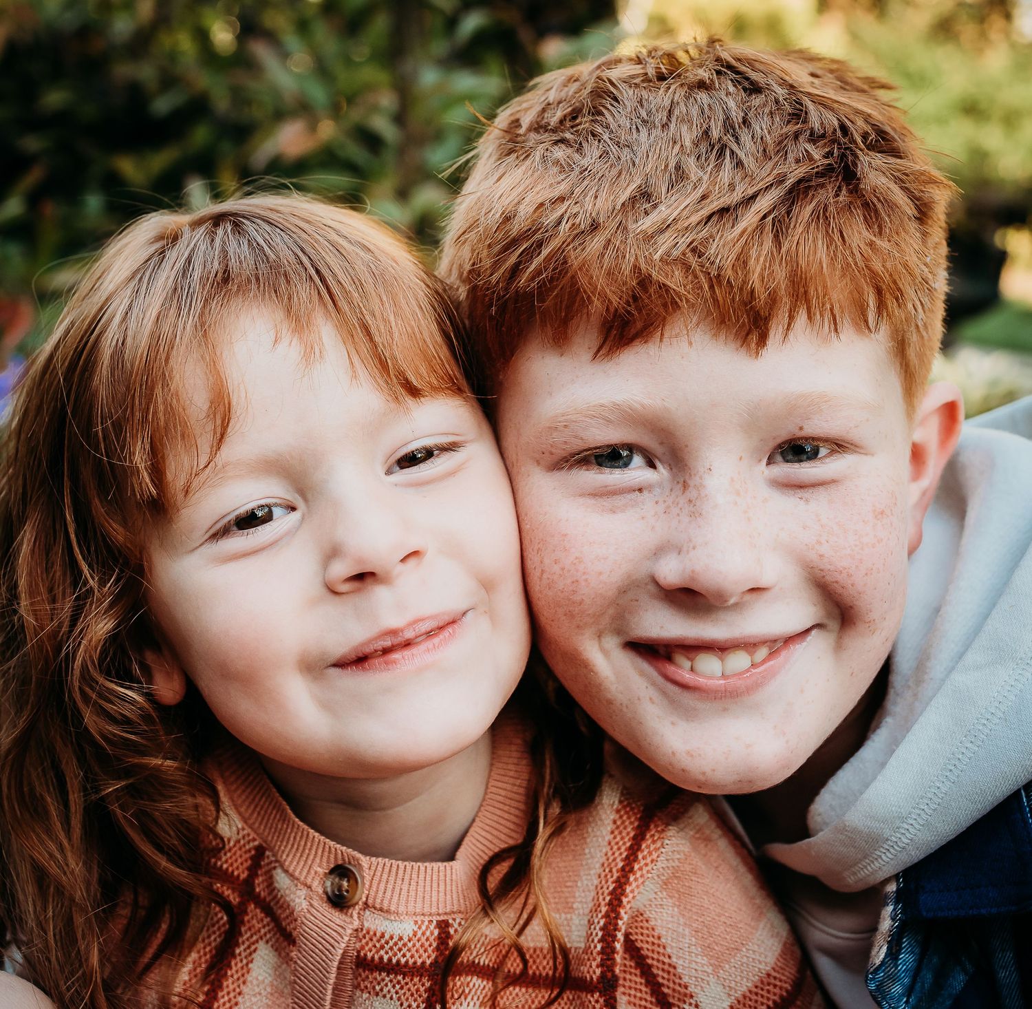 Two young friends smile warmly at the camera in an intimate close-up portrait.