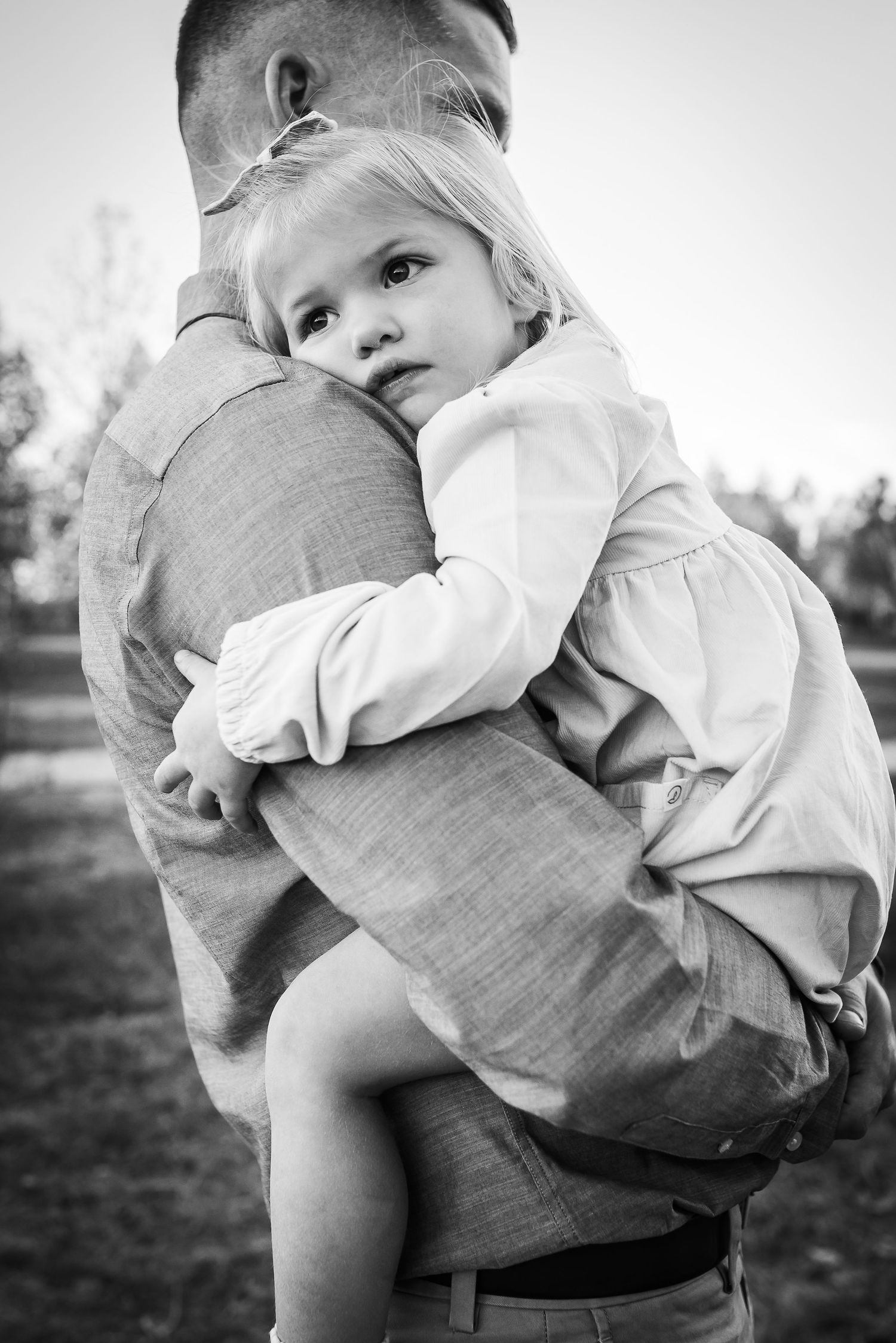 A black and white portrait capturing a tender embrace outdoors.