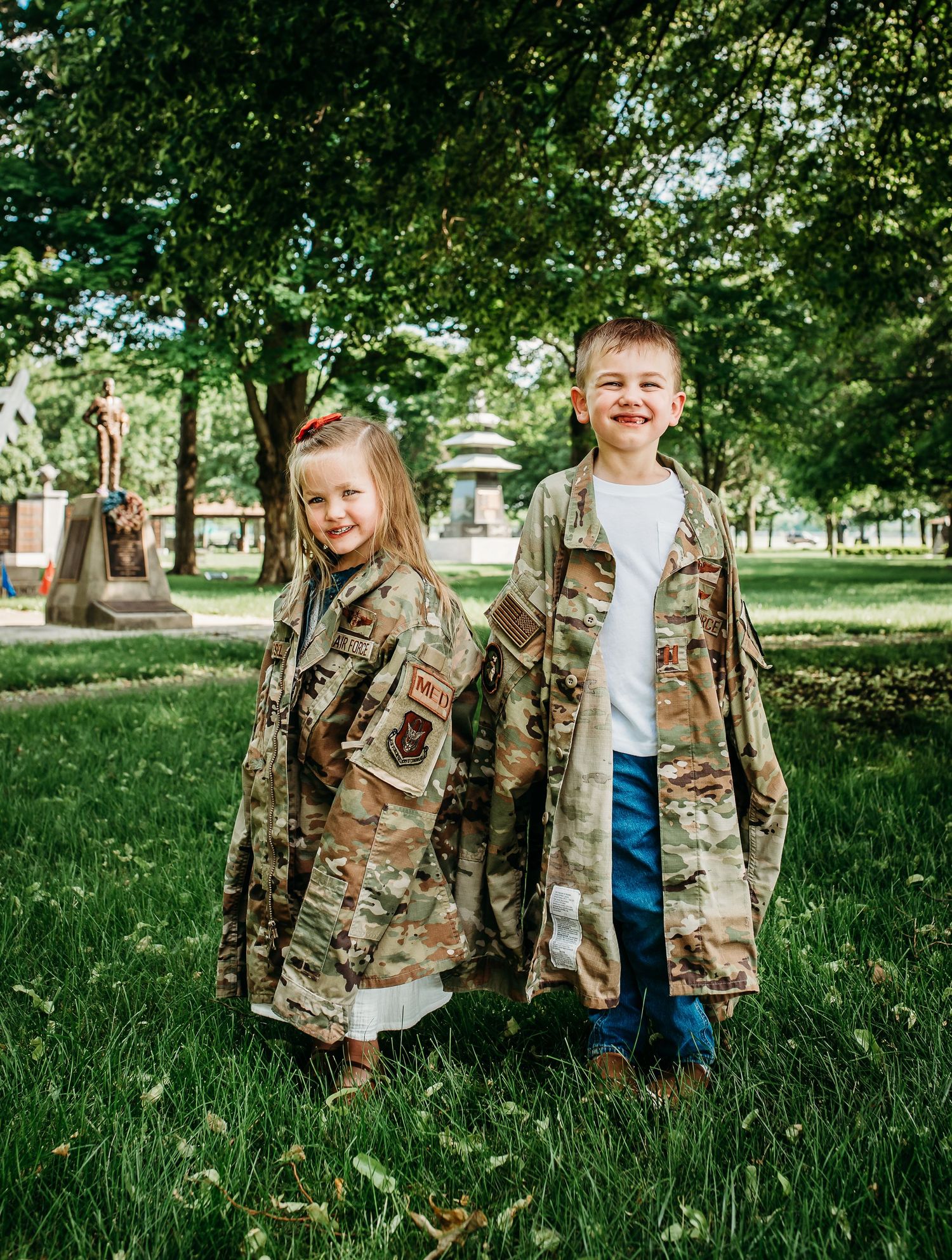 A family wearing military camouflage uniforms stands together in green grass.