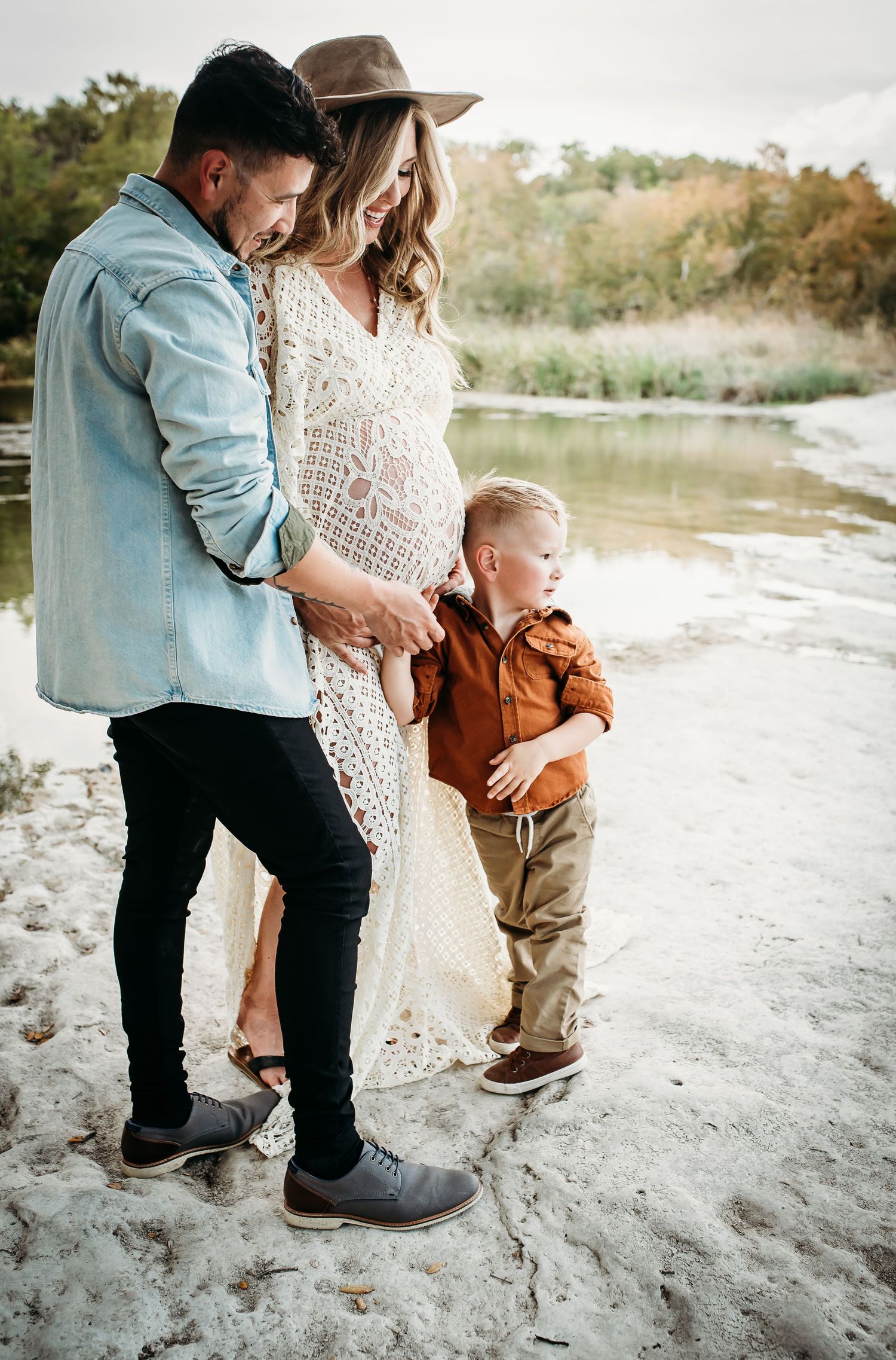 An intimate family portrait on a sandy riverbank during golden hour.