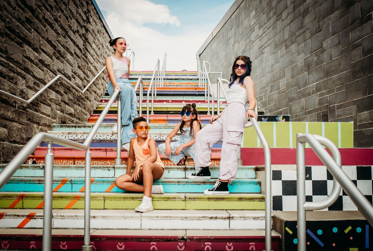 Friends relaxing on vibrant rainbow-colored stadium steps in urban setting.