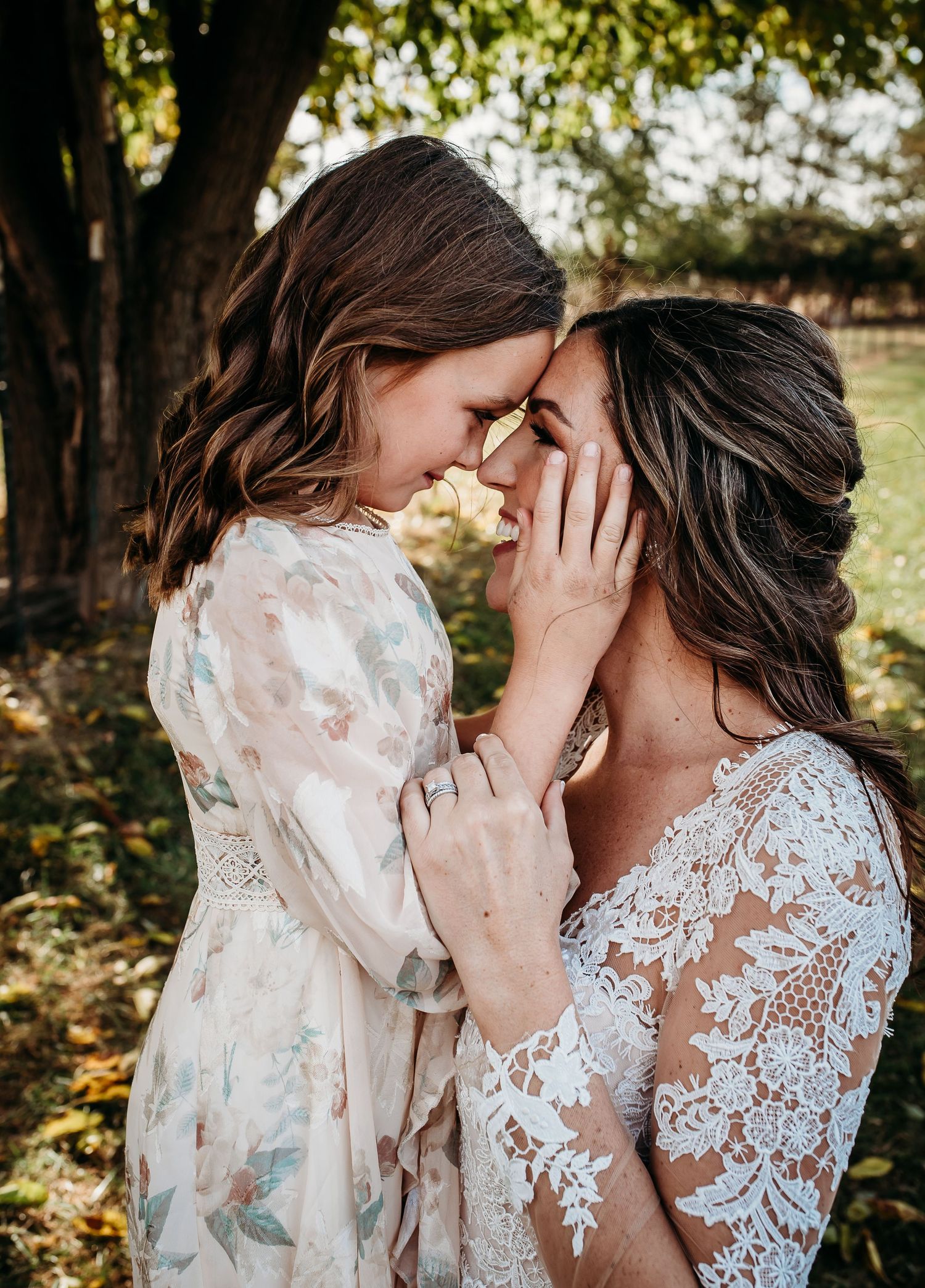Intimate emotional moment shared between two people in wedding attire under autumn trees.