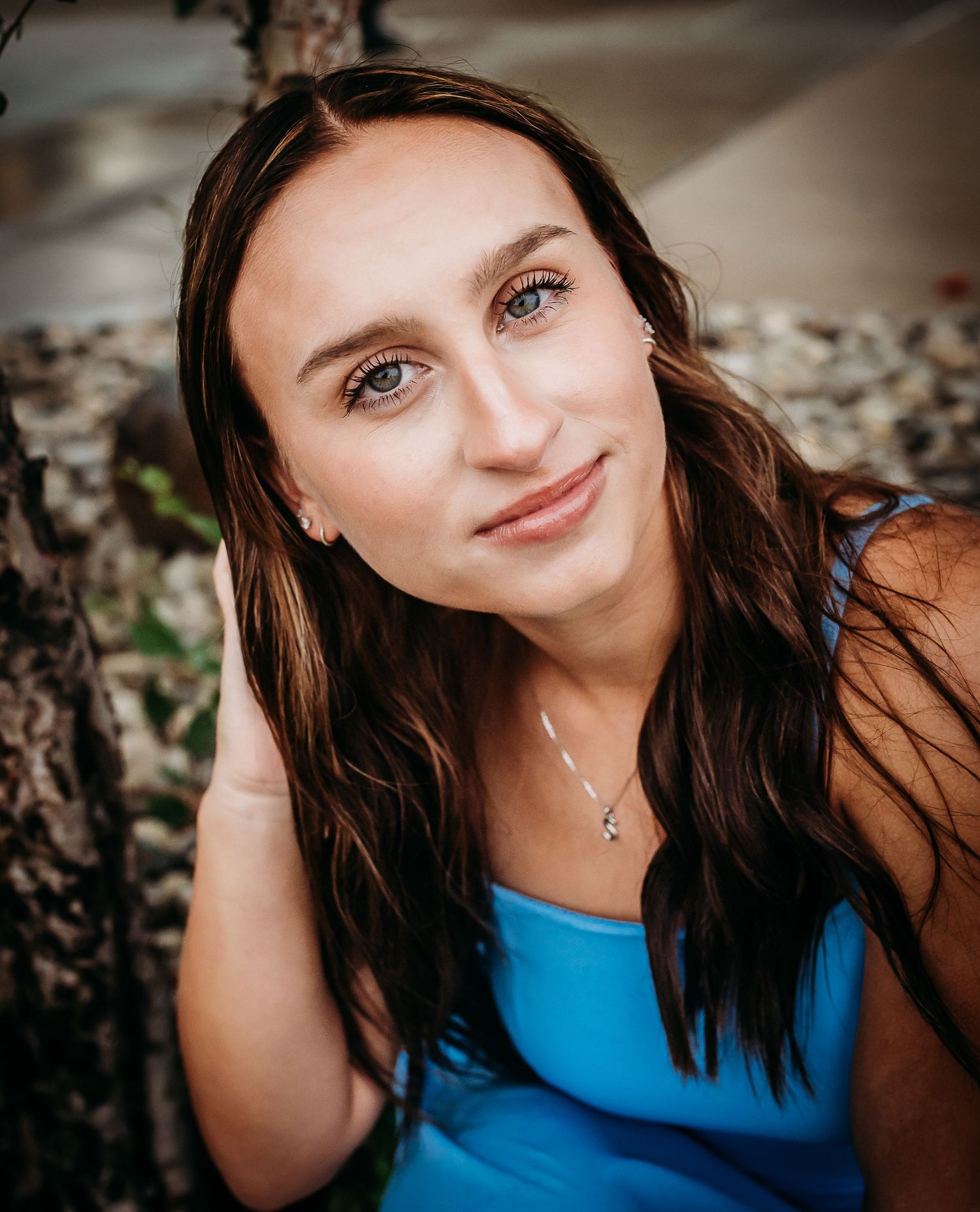 A series of closeup portrait shots of someone in a bright blue top against a dark background.