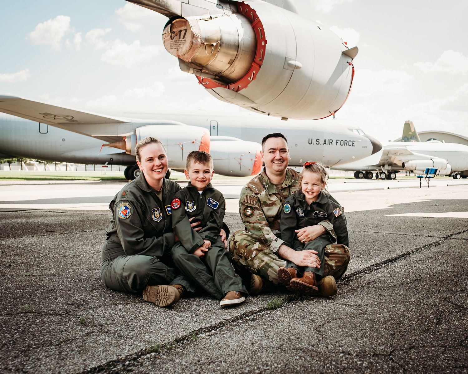 Military personnel posing playfully beneath an aircraft wing.