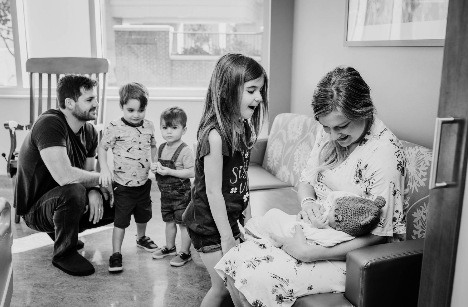 Hospital staff gathers around during an intimate newborn photography session in black and white.