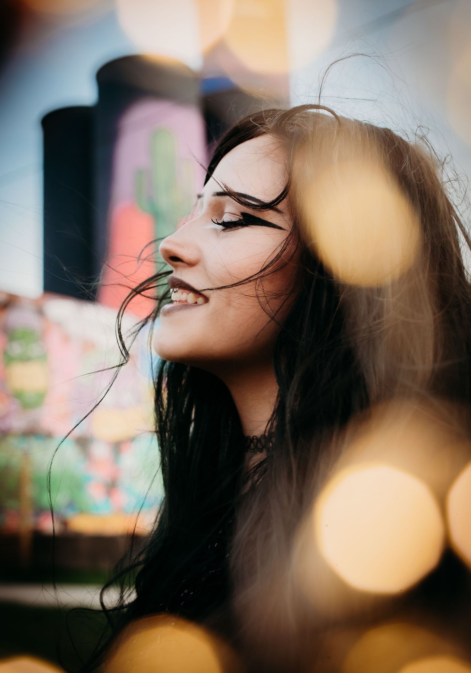 Artistic profile portrait with bokeh lights showing person with long dark hair and closed eyes.