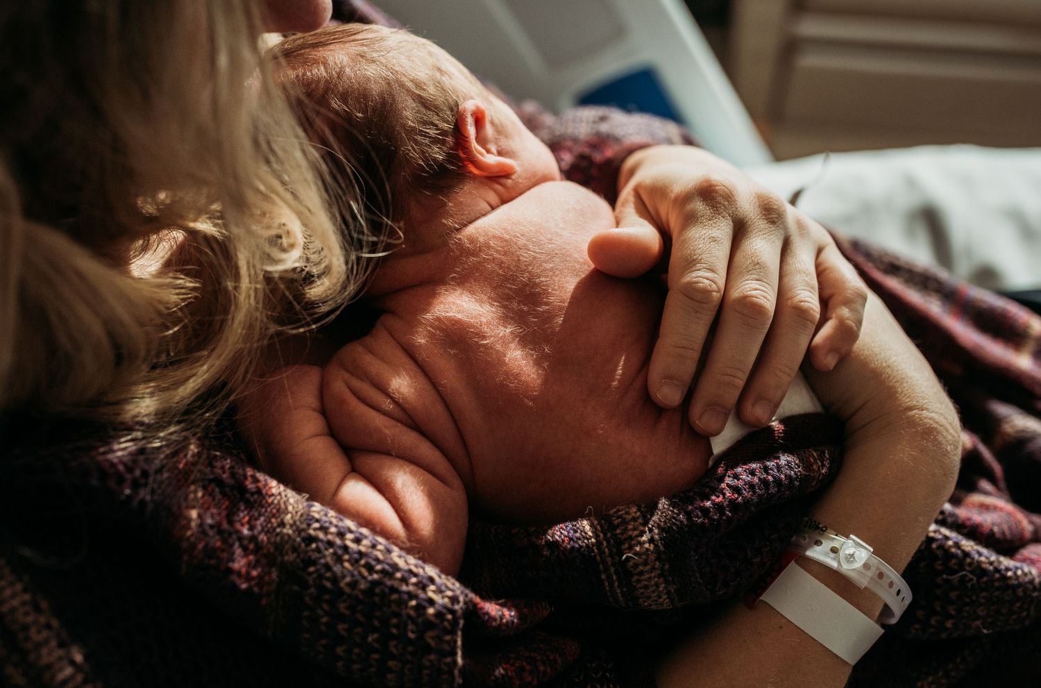 Intimate bonding moments with newborn in soft window light.