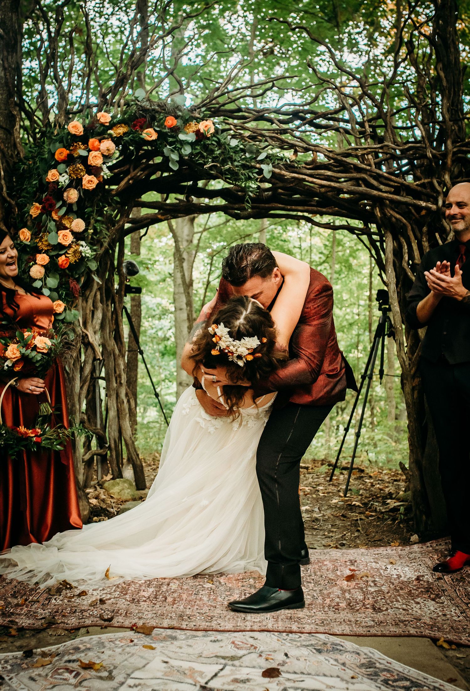 Romantic wedding ceremony under natural arch decorated with orange lanterns and greenery.