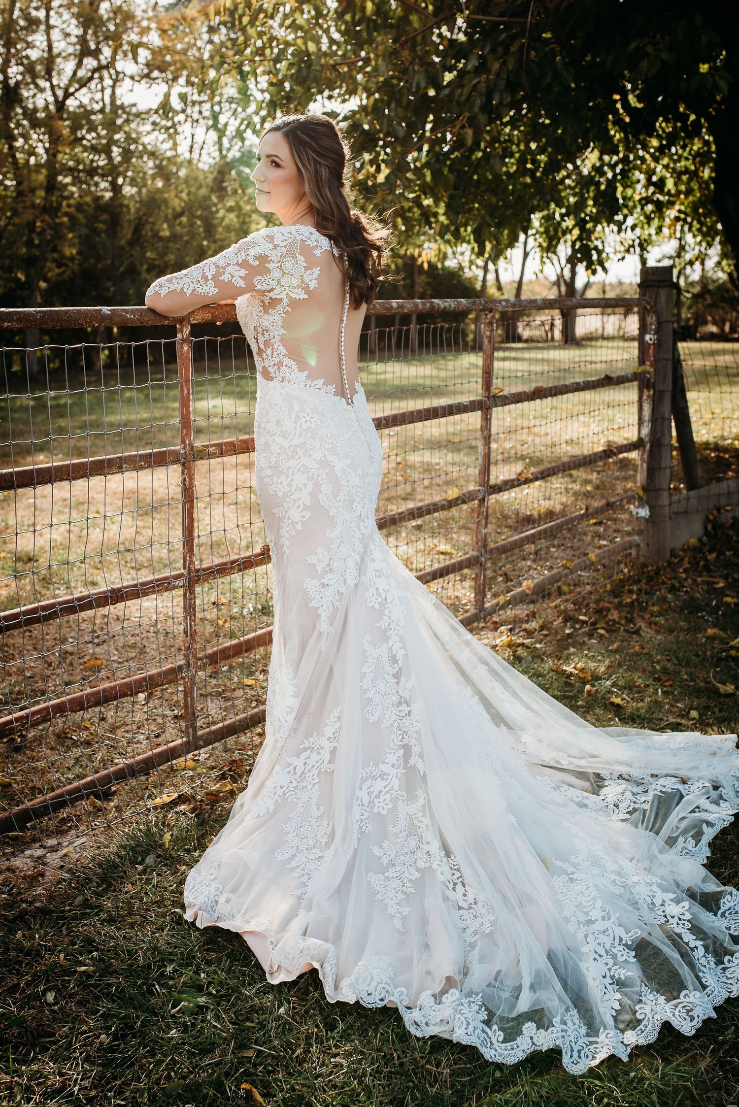 Beautiful lace wedding dress with flowing train captured in sequence against rustic fence.