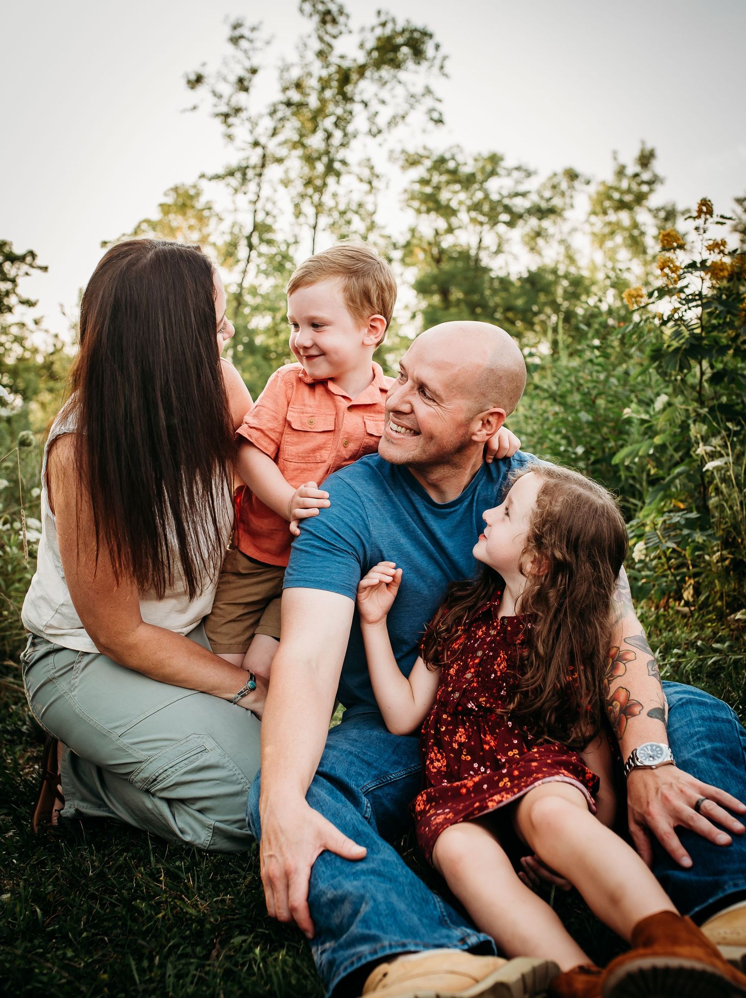 Candid family portrait shows joyful laughter while sitting together outdoors.