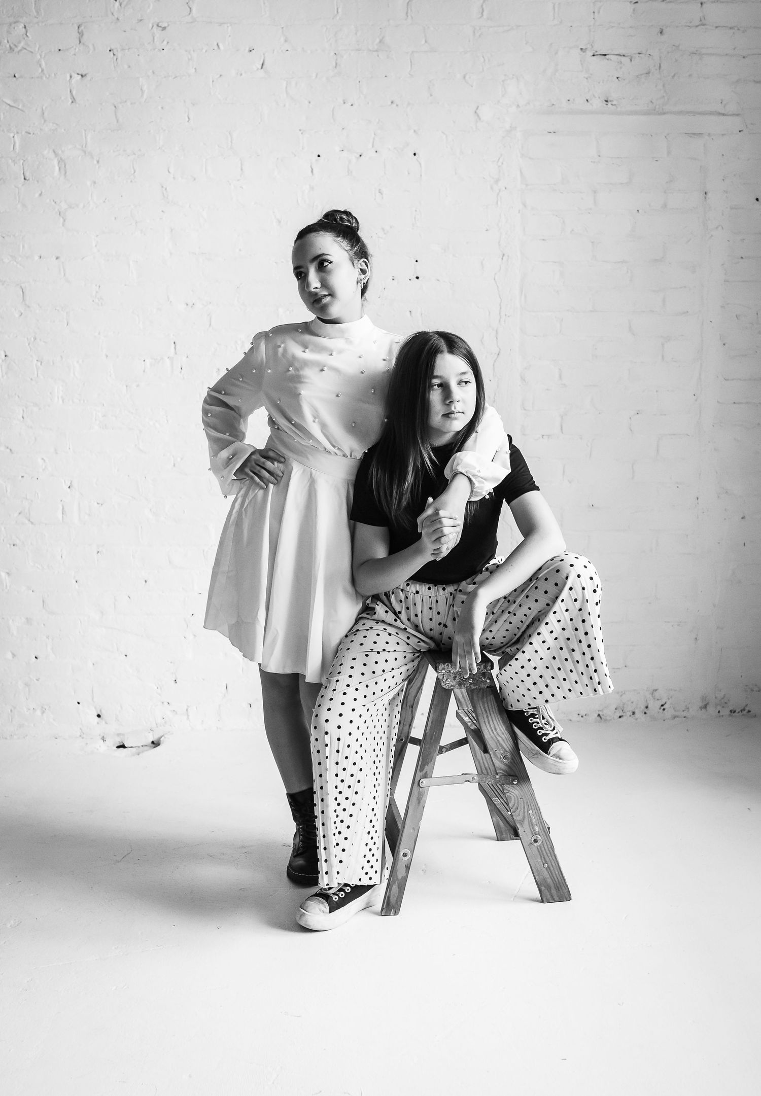 Two people pose in contrasting outfits during black and white studio photoshoot.