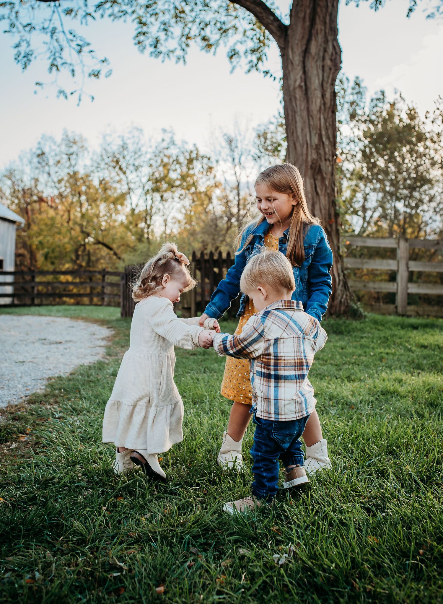 A joyful group plays together on green grass with a rustic fence in the background.