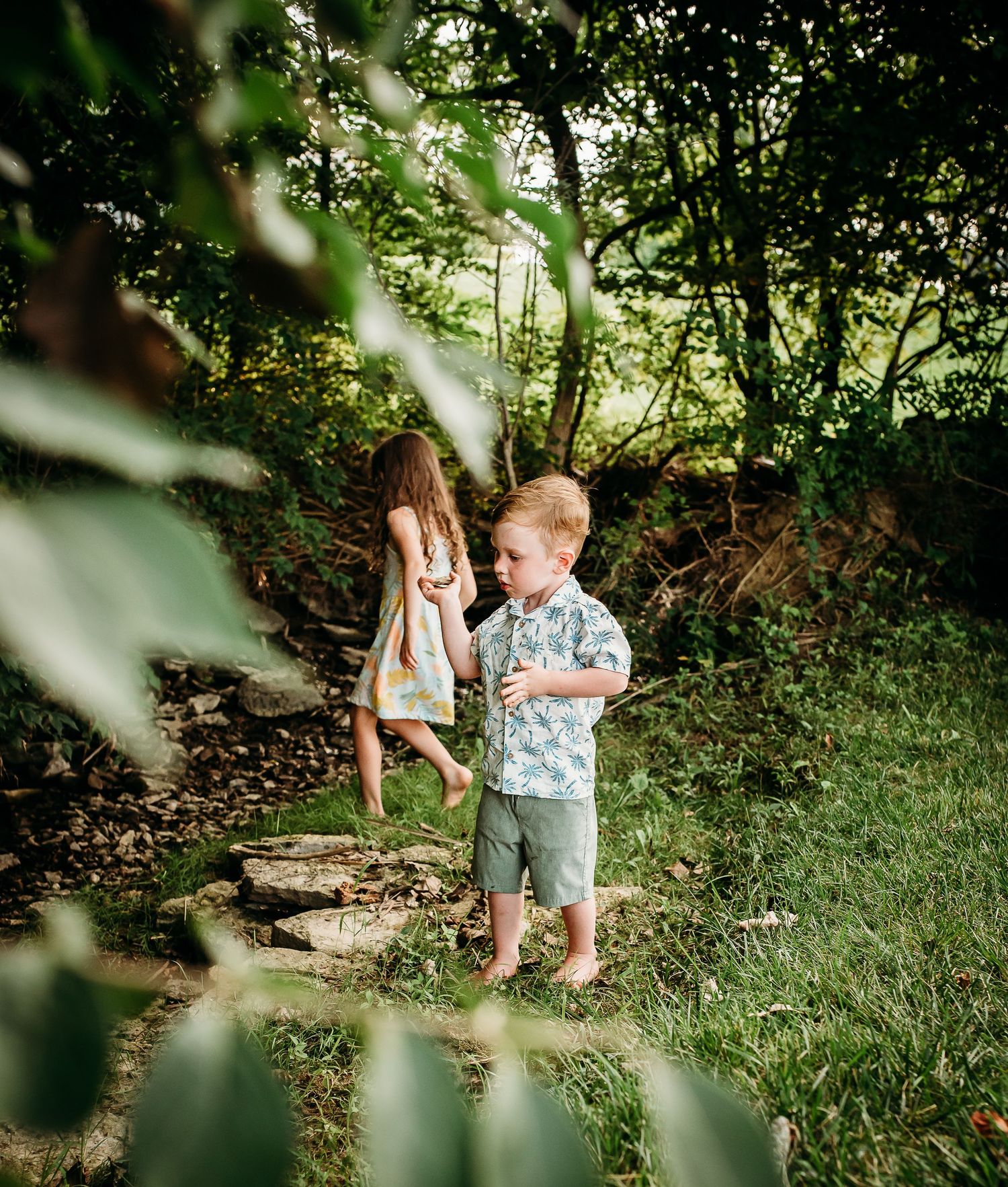 Two small figures walking along stone steps in a lush garden setting.