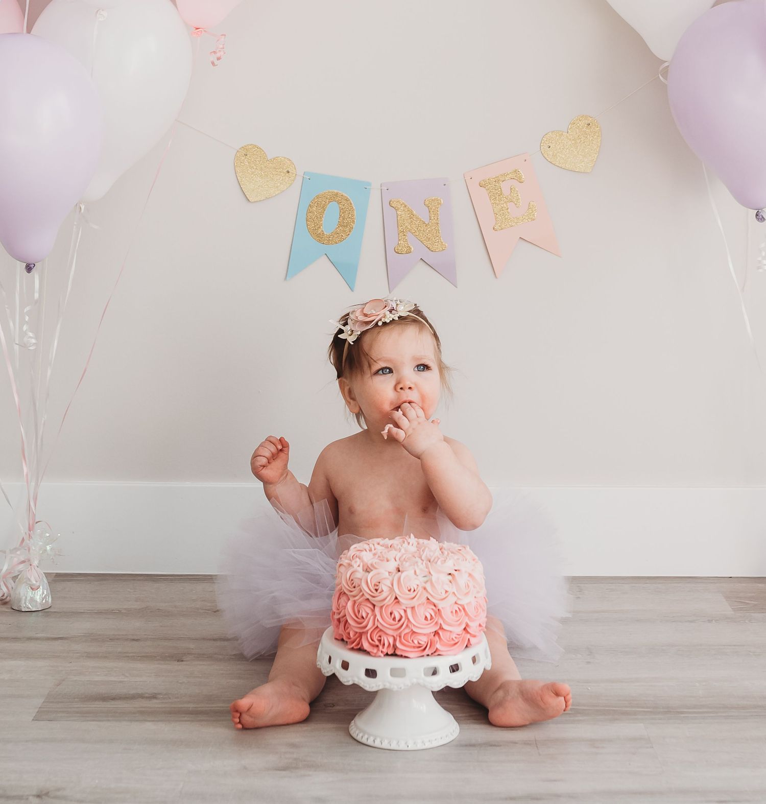 A first birthday celebration setup with a cake smash scene and pink and gold decorations.