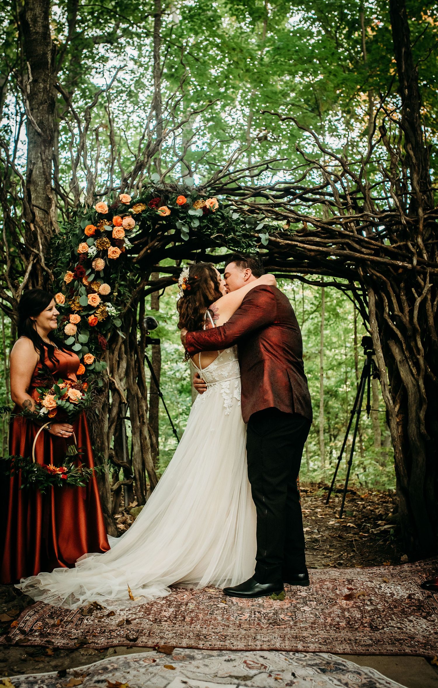 A romantic first kiss under a flower-adorned wooden arch in the forest.