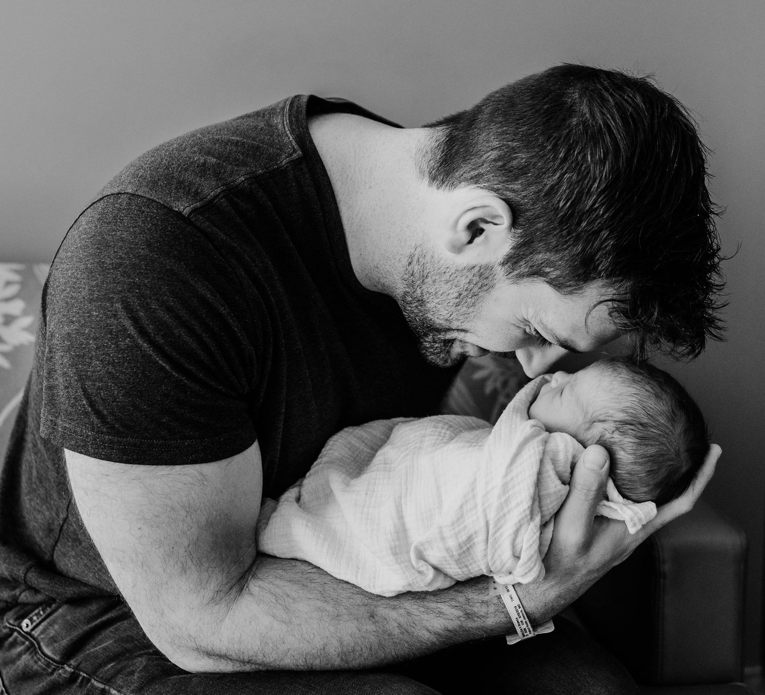 Intimate black and white portrait of a tender moment between parent and newborn.