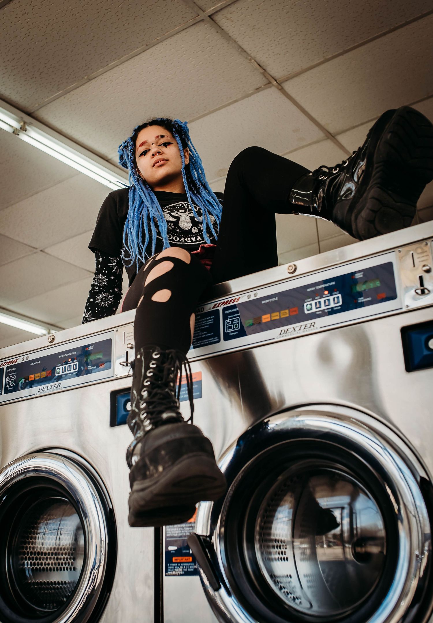 Artistic laundromat photoshoot with washing machines and colorful hair.