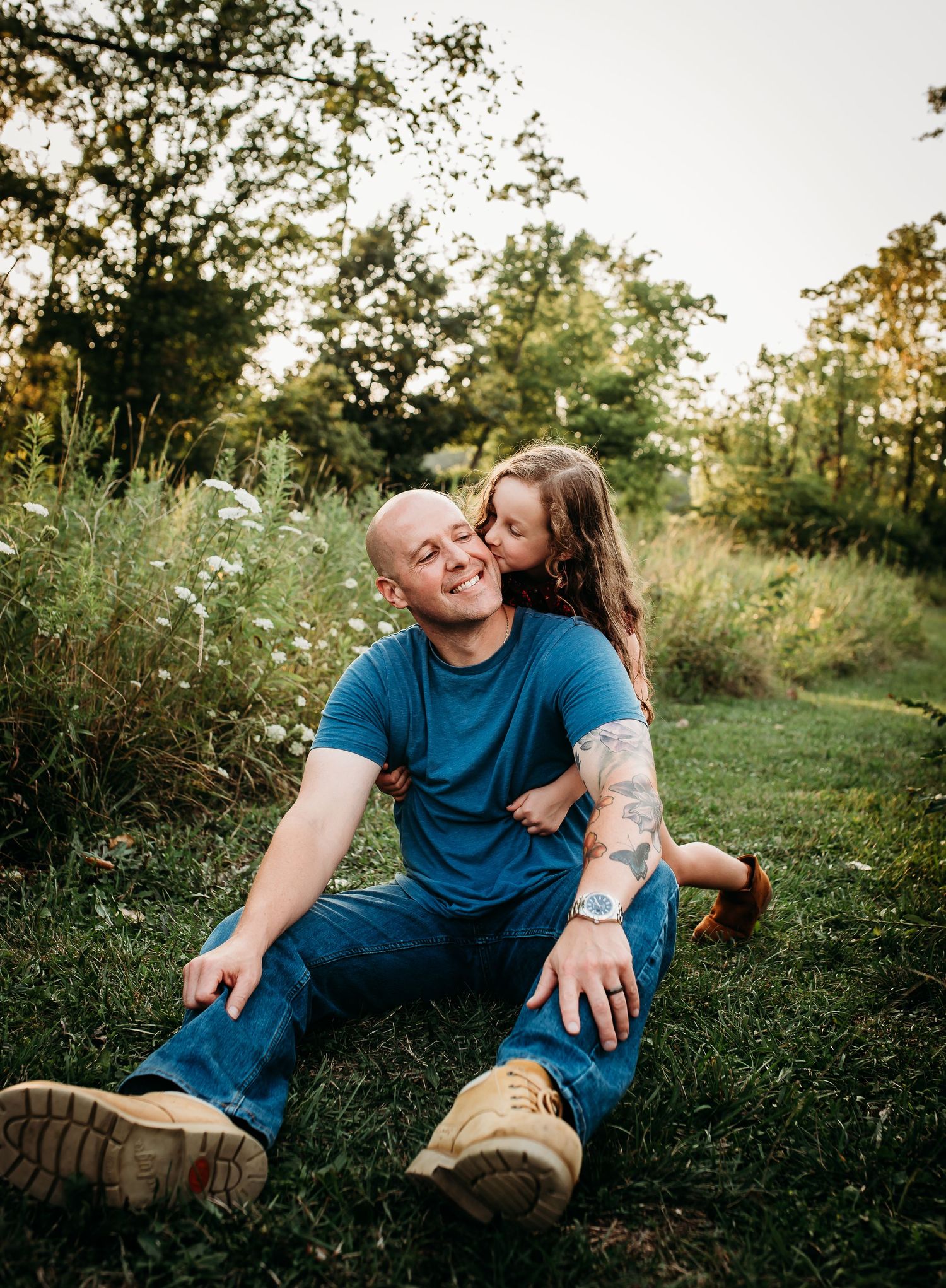 Family sits together on grassy hillside during sunset photoshoot.