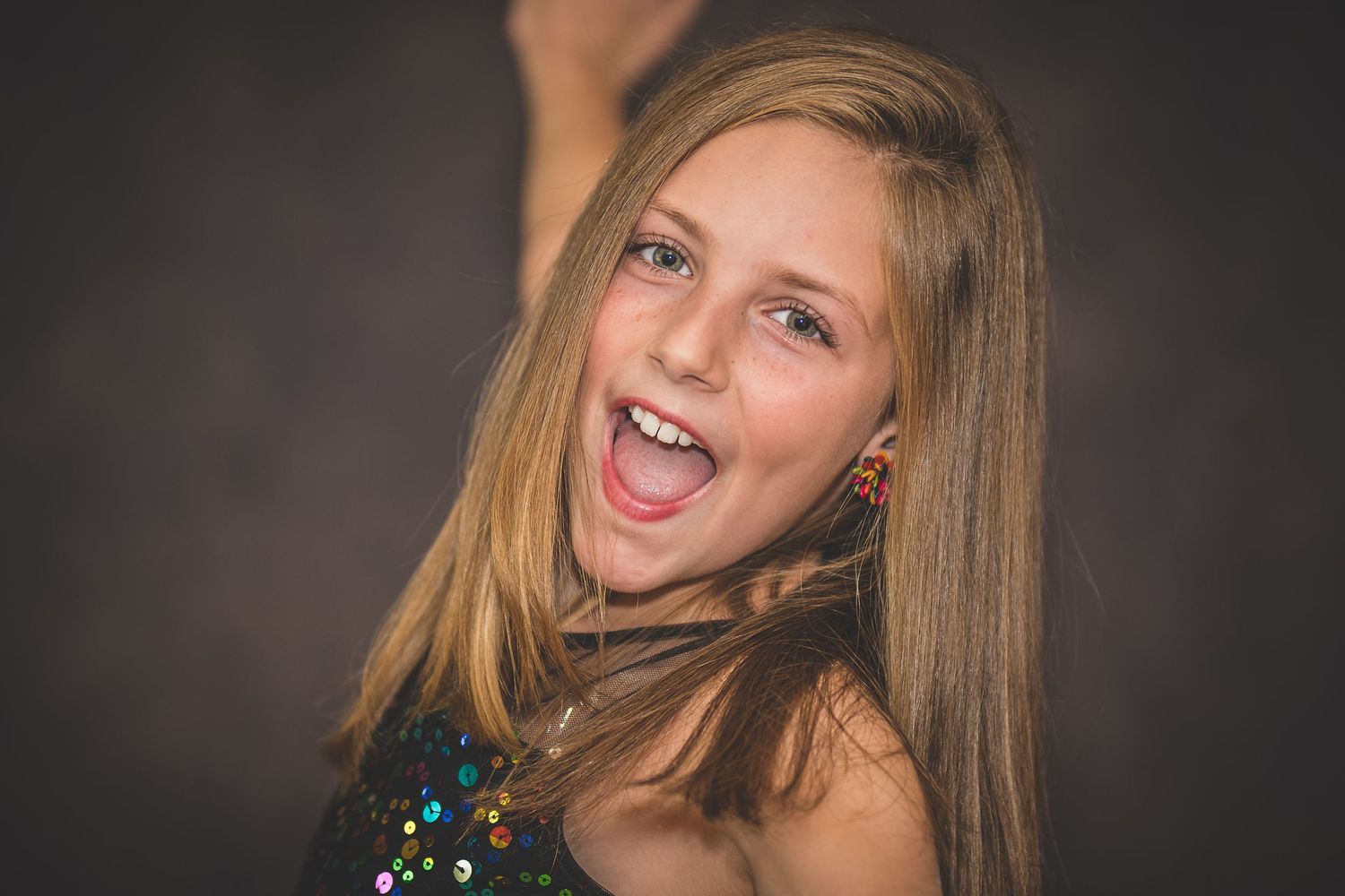 Studio portrait showing joyful expression against dark background.