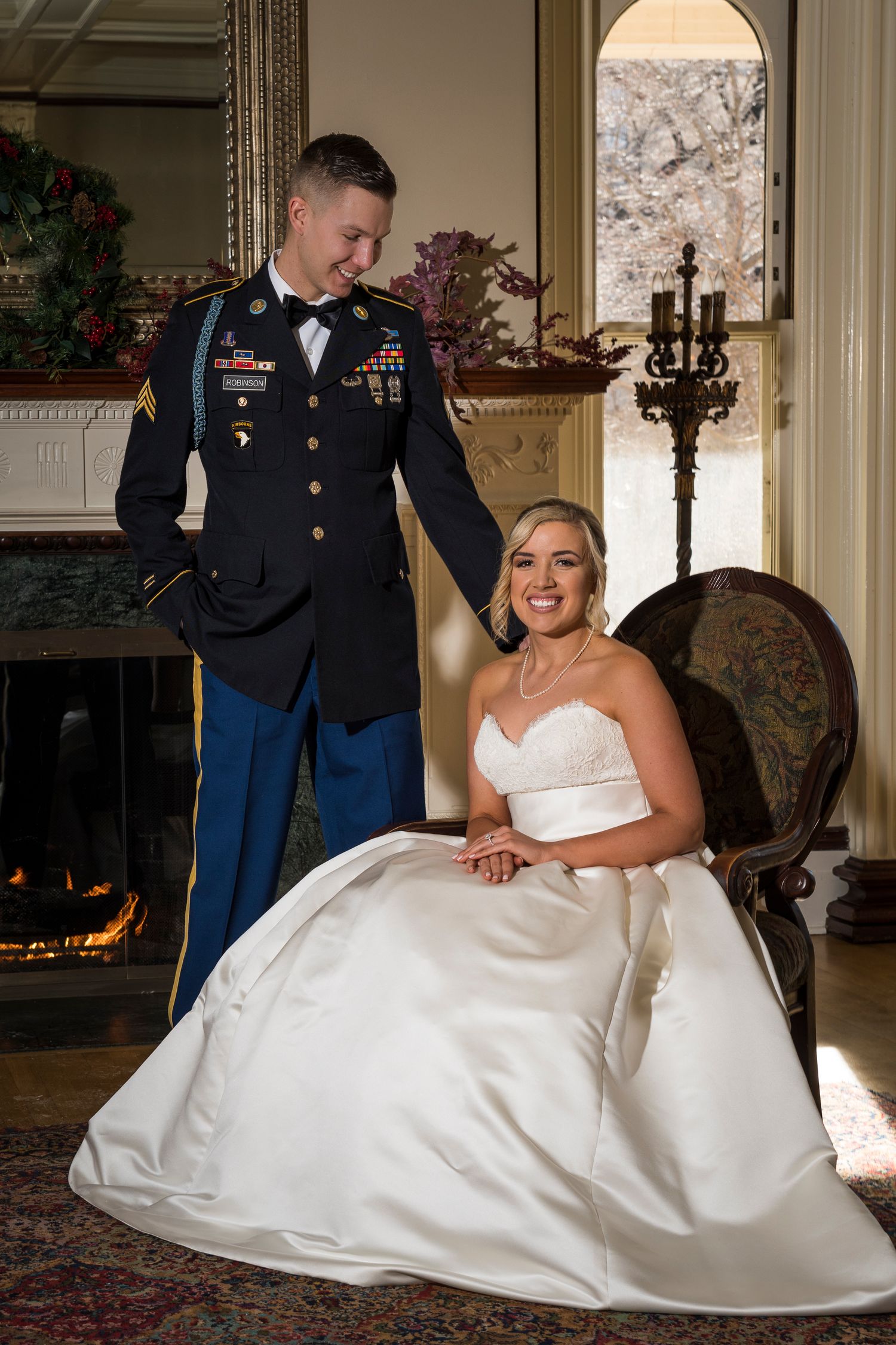 Military wedding portrait in elegant room with fireplace and ornate decor.