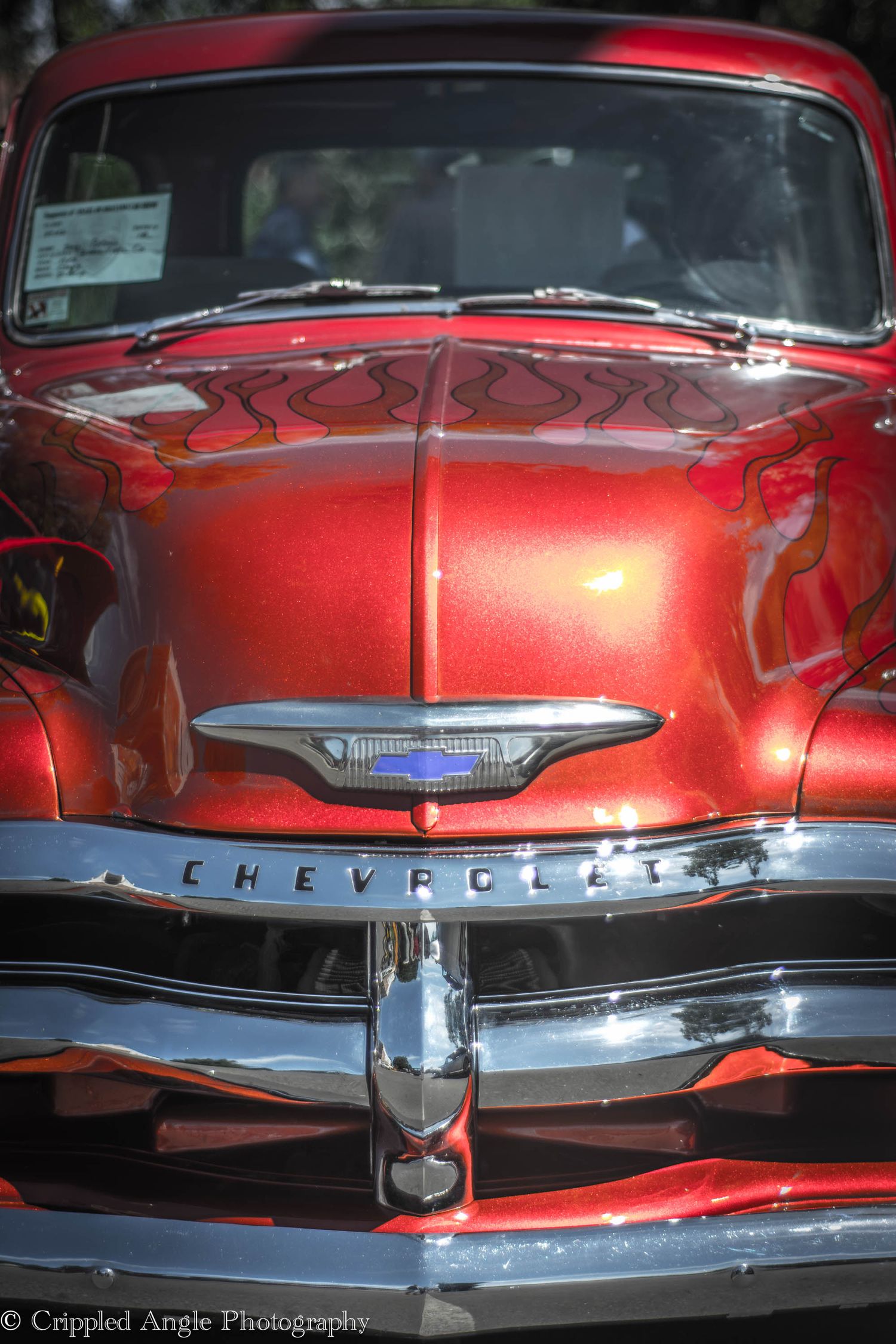 Close up of classic red Chevrolet car front grill and hood ornament.