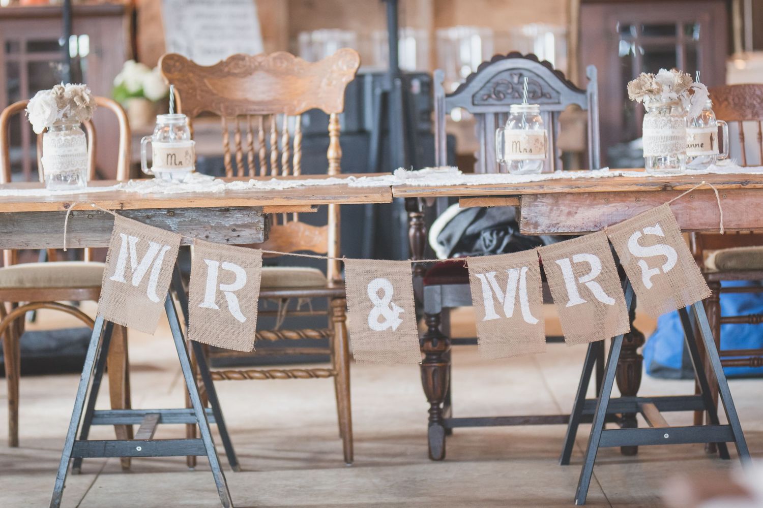 Rustic wedding reception table with Mr & Mrs burlap banner and vintage decor.