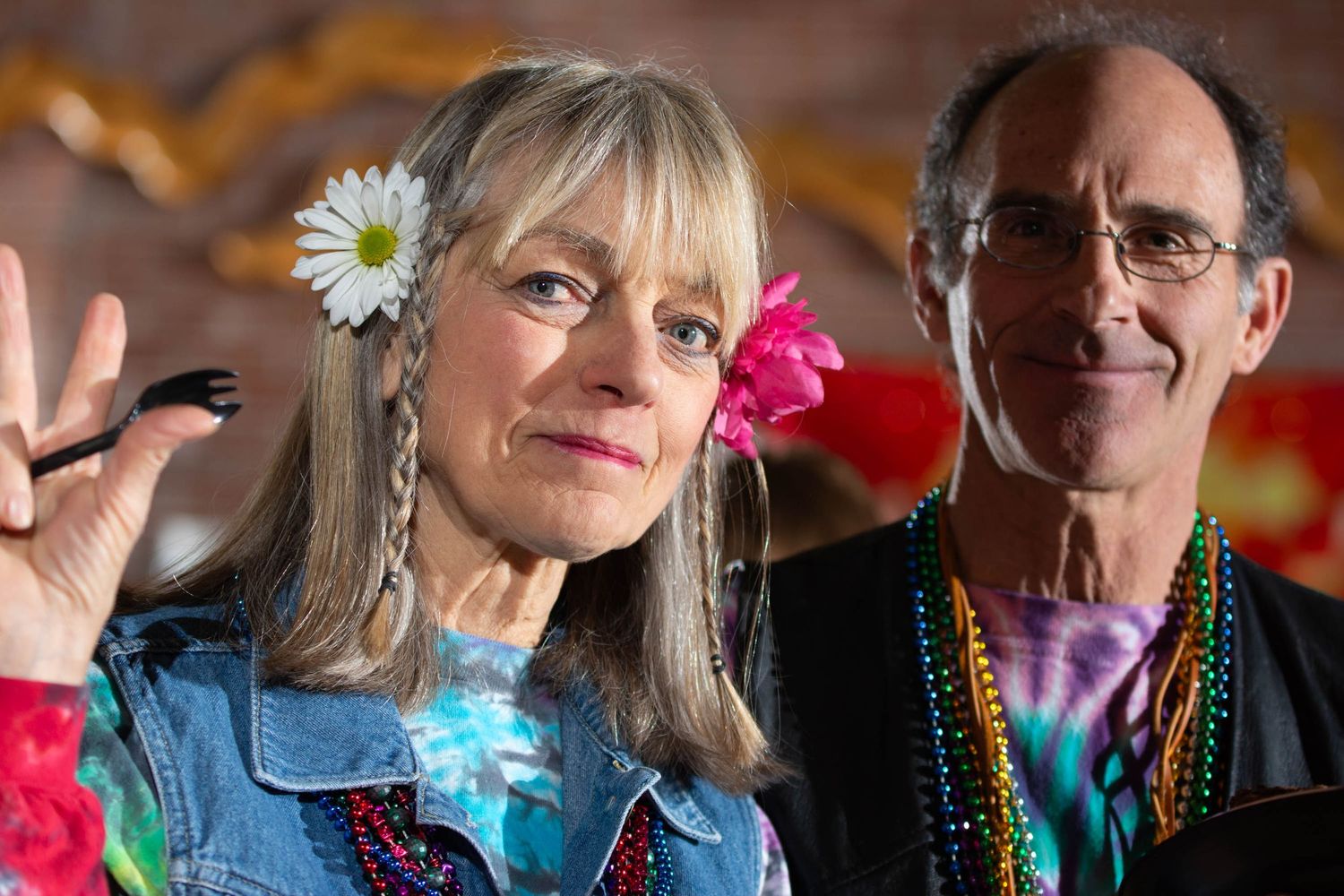 Two people in festive attire with flowers in their hair at a celebration.