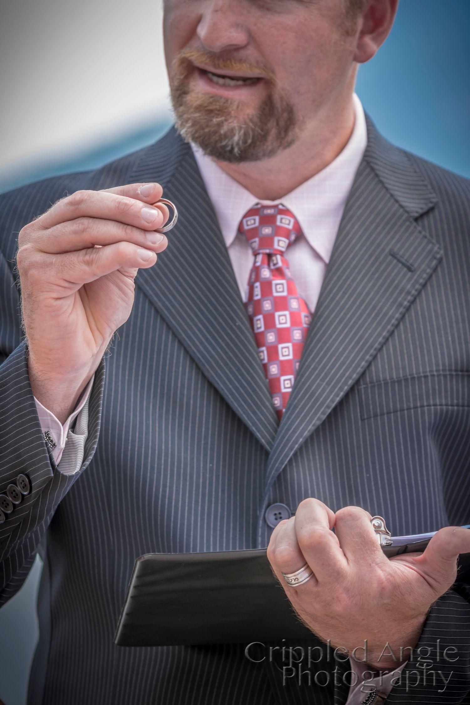 Professional in pinstripe suit and red patterned tie checks something on a mobile device.